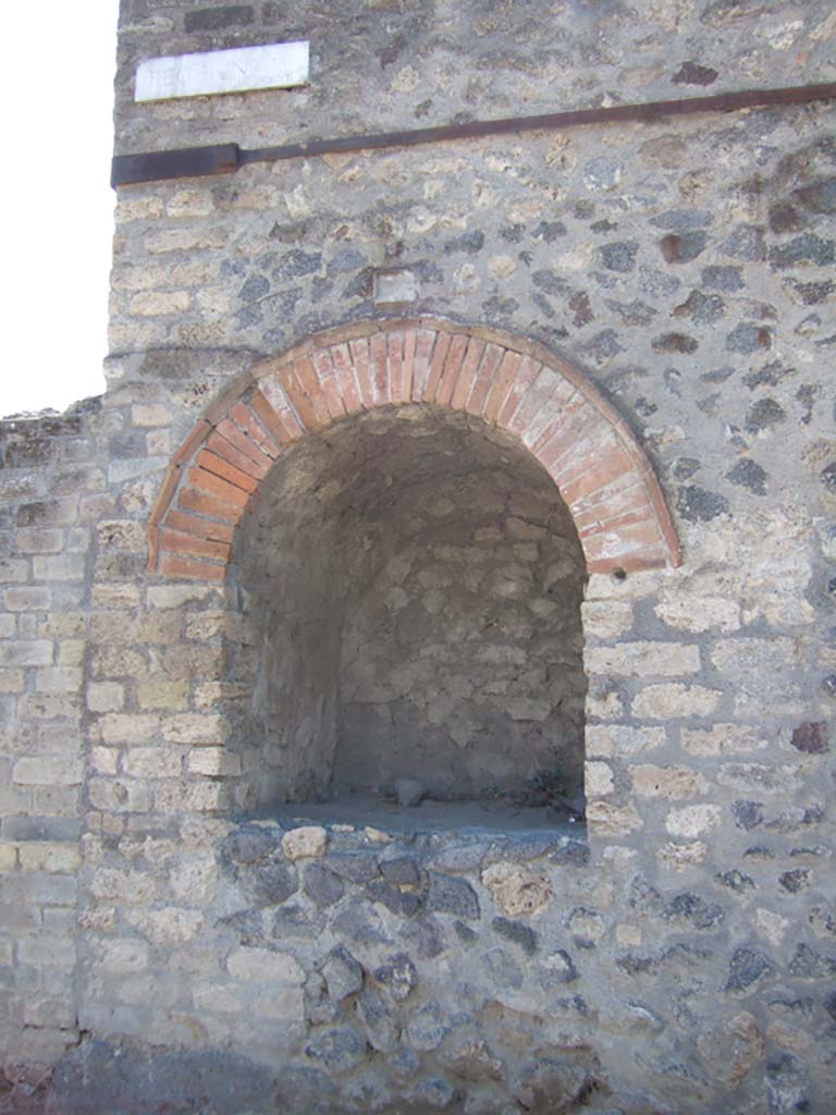 Pompeii II.4.7a. September 2005. Street shrine at east end of II.4 on Via dell’Abbondanza.
According to Van der Poel, this great niche, which was used as a compitum, was discovered by Spinazzola in 1912.
See Van der Poel, H. B., 1986. Corpus Topographicum Pompeianum, Part IIIA. Austin: University of Texas. (p. 46).
According to Della Corte in NdS –
“Entirely excavated was an important public shrine fronting the roadway, and resulting in a rounded arched niche, 1.22m high; 1.06m wide; 1.08m deep, adorned above by a beautiful, raised stucco cornice. The niche which opened onto the pavement at the height of the breast of a man, was, as seems certain, a small temple in which the Penates and the protecting Divinity of Pompeii were worshipped.”
See Notizie degli Scavi di Antichità, 1912, (p.68).