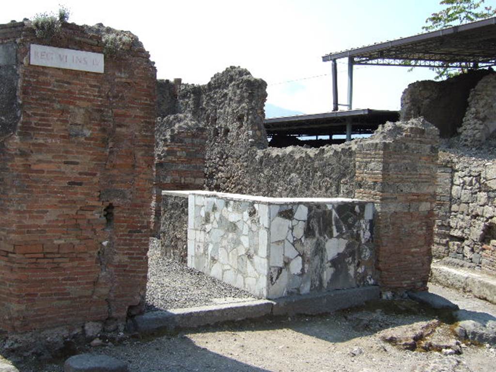 VI.4.1 Pompeii. May 2006. Entrance doorway with counter. 
According to Curti, in 1818, in the face of the Via Domiziana [todays Via Consolare], on the corner of a triangular insula, was found a taberna of a seplasarius [a trader in perfumes and unguents] or a pharmacist. For exhibition, he had painted a large snake that bites a pine cone. The serpent was the attribute of Hygeia, the goddess of health, and of Aesculapius: it is still the emblem of today's [1873] pharmacies. In Pompeii, as we have noted elsewhere, it was valid for other purposes, and therefore would not have been enough to fix the designation of this taberna as a pharmaceutical workshop, had it not been found inside various other medicines, chemical preparations, pots with dried medicines and pills, spatulas, and a bronze box with compartments containing drugs, and a porphyry blade to spread and smooth the poultices.
See Curti P. A., 1873. Pompei e le sue rovine: Part 2. Napoli e Milano, p. 268.
According to Della Corte, this thermopolium or workshop was always described in the old bibliographies as an �officina farmaceutica�
Why?  Many chemical preparations and many jars with dried medicines and pills were found here.
As medical substances, they are unknown, however as the results have never been analysed. 
The notion that it was an �officina farmaceutica�, however was, and stays, simply circumstantial.
See Della Corte, M., 1965.  Case ed Abitanti di Pompei. Napoli: Fausto Fiorentino. (p.42)
