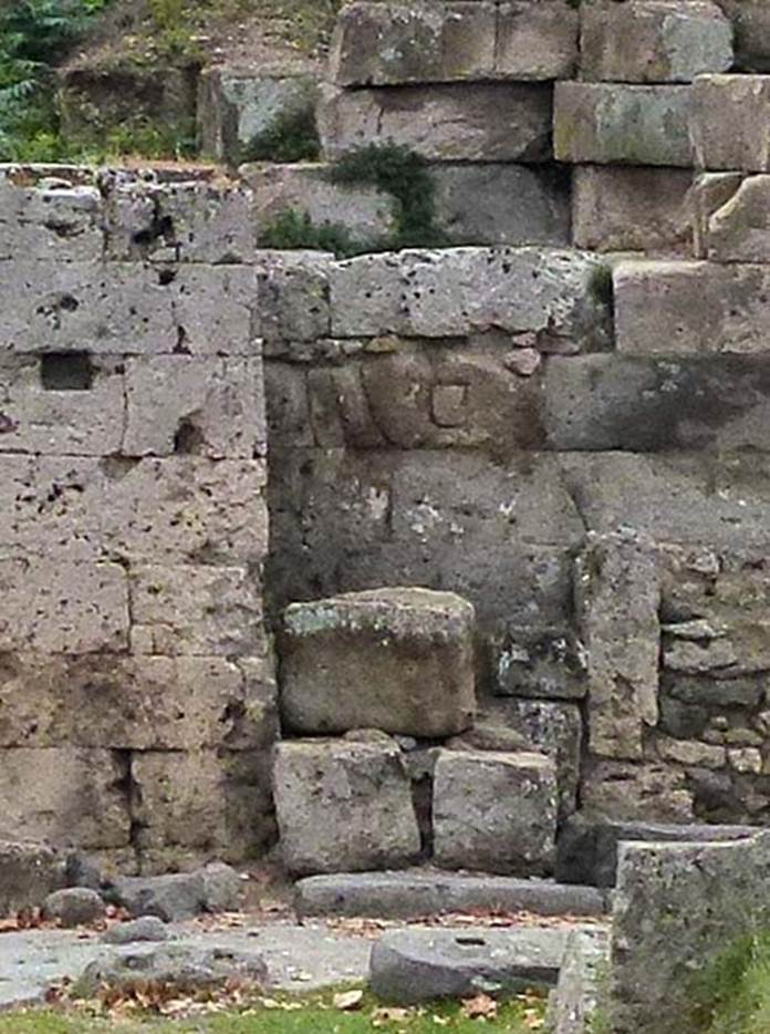 Two altars at Pompeii Vesuvian Gate. September 2011. West wall of gate and site of two altars. According to Sogliano, the larger altar was in the wider part of the recess [d on the plan]. It had edges in relief and was dressed entirely in plaster and with a painted representation which was completely unrecognizable. Next to this altar there was another [e on the plan], in a narrow part to the right (north) at the rear. It was much smaller, and also had an edge in relief. They were certainly devoted to worship of Lari Pubblici and to the guardian deity of the gate, whose representations would have been painted on the walls, in which the two altars were huddled. See Notizie degli Scavi di Antichit�, 1906, p. 97-100.
The three gate stones can be seen on the ground to the left. Detail from photo courtesy of Michael Binns.