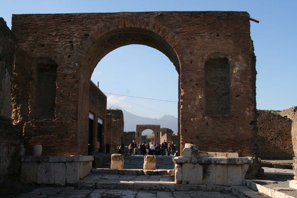 Arch at north-east end of the Forum. April 2013.
South side, looking north through arch onto Via del Foro, and towards Arch at south end of Via di Mercurio, with Vesuvius in the distance.
Photo courtesy of Klaus Heese.