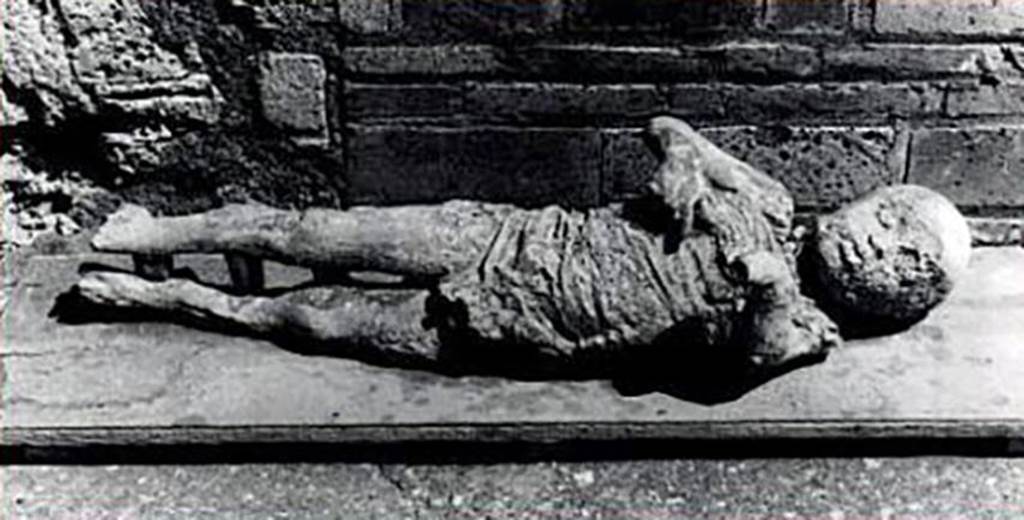 VI.17.42 Pompeii. Victim 53. 1978, cast of a child found in a corridor a few metres from the three other bodies.
Part of a group of four who died under the staircase.
Victim 51 is now identified as a male aged less than 6 and probably around 3 years old.
The body was found in corridor 10 of the Casa dell Bracciale d’Oro between January and July 1978.
Imprints of a short, sleeveless tunic, perhaps made of linen, are clearly visible on the torso.
See Osanna, N., Capurso, A., e Masseroli, S. M., 2021. I Calchi di Pompei da Giuseppe Fiorelli ad oggi: Studi e Ricerche del PAP 46, p. 444-5, Calco n. 53.


