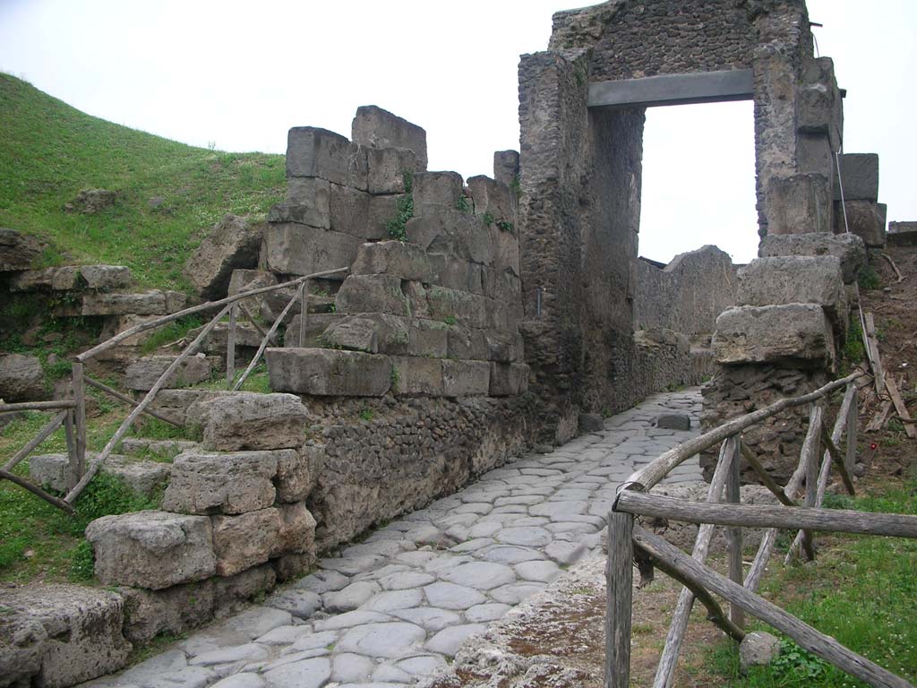 Porta di Nocera or Nuceria Gate, Pompeii. May 2010.Looking towards west side of gate. Photo courtesy of Ivo van der Graaff.
According to Van der Graaff –
“The current structure repeats the familiar layout: outer travertine bastions, a tuff gate court, and a concrete vault.
In the traditional view, each element should represent a separate construction event. The remains tell a different story.
The foundations of the gate are visible because engineers lowered the road passing through it after the establishment of the Roman colony (Note 67).
Proof of this arrangement comes from simple observation.
The sidewalk leading up to the gate, as well as the struts that once supported the gate leaves, are unduly high in comparison to the road.
The lowest four courses of the masonry composing the gate court display quarry marks and are laid down as ashlars.
By contrast, the upper courses stand vertically as orthostats and are dressed to a smooth surface.
All of the masonry of the gate court stands on a thick opus incertum foundation.
This concrete base displays a seamless tradition with the masonry of the vault behind it. (See Plate 11, as above photo).”
See Van der Graaff, I. (2018). The Fortifications of Pompeii and Ancient Italy. Routledge, (p.60).
On page 62, he continues –
“Nevertheless, given the massive expansion of the agger, the current layout of the Porta Nocera must be contemporaneous with the upgrade of the adjacent fortifications that occurred in the second century BCE (Note 70). This date makes the Porta Nocera a laboratory of sorts for the application of opus incertum as a new construction technique.”