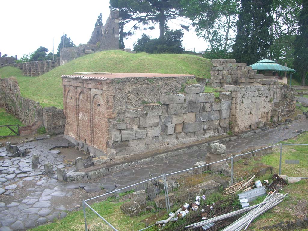 Vesuvian Gate, Pompeii. May 2010.
Looking north-west from south end, with Castellum Aquae leaning against west wall, in centre, with narrow sidewalk, and Tower X, in background.
On the left are lava cippi, as described by Sogliano, and apparently acting as kerbstones. Photo courtesy of Ivo van der Graaff.