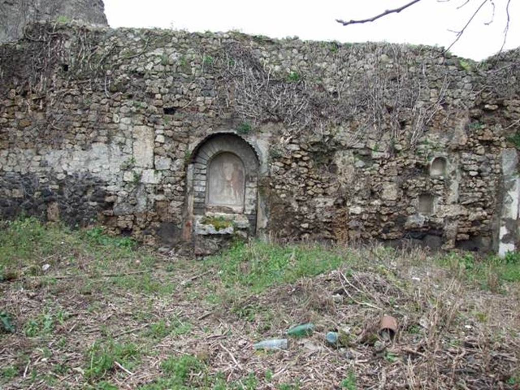 VII.11.14 Pompeii. March 2009. Garden “C”, west wall.
According to Boyce –
Against the west wall of the large open area in the south-west corner, stands a lararium.
Above a rectangular podium (0.95 by 0.60, h.105) a projecting arch was built against the back wall, thus forming a niche (h.1.02, w.0.70, d.0.32).
The front part of the upper surface of the podium served as an altar for sacrifices before the figures painted on the walls of the niche, on the front side of the podium was a step.
On the rear wall of the niche are painted Jupiter and the Genius, each pouring a libation upon the blazing cylindrical altar between them.
Jupiter stands on the right, on the left is the Genius.
To the right and left on the wall outside the niche were the poorly preserved figures of the Lares.
The side walls and the vaulted ceiling of the niche were decorated with leafy boughs.
The exterior of the structure was coated with stucco painted in several different colours.
See Boyce G. K., 1937. Corpus of the Lararia of Pompeii. Rome: MAAR 14. (p.69, no.310 with Pl.14,1)