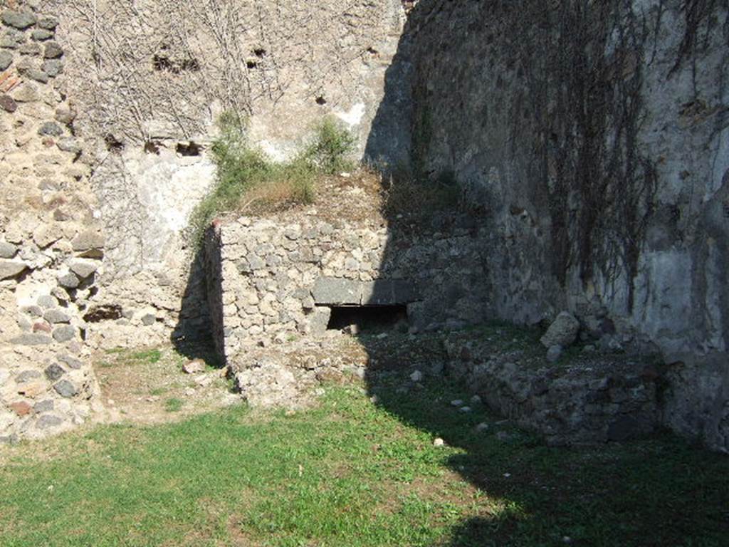 VII.12.7 Pompeii. September 2005. Looking east towards oven in south-east corner of rear area.
According to Boyce, on the south wall of the room with the oven was a large lararium painting (2.0 square).
In the centre was a blazing tripod, with the Genius to the right of it.
On each side was a wreathed Lar.
To the left of this group stood Vesta, at her side was an ass with a bell around its neck.
On the right of the group stood Mercury.
In the lower zone, marked off from the upper by a brownish stripe, were the two serpents.
They were approaching a gold-coloured altar, on top of which was a white shallow dish containing a blazing fire.
In the fire was an egg and several fruits – a date, a pomegranate and a medlar.
See Boyce G. K., 1937. Corpus of the Lararia of Pompeii. Rome: MAAR 14. (p.70, no.313).
See Helbig, W., 1868. Wandgemälde der vom Vesuv verschütteten Städte Campaniens. Leipzig: Breitkopf und Härtel. (68)
According to BdI, this was the first time that Mercury appeared associated with the Lares, in Pompeii.
See Bullettino dell’Instituto di Corrispondenza Archeologica (DAIR), 1864, p.114-115 (described as Casa II.)