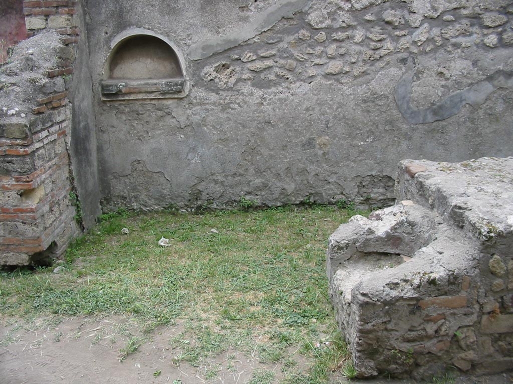 VII.12.15 Pompeii. May 2003.
Looking towards west wall, with niche. At the end of the counter, the hearth can be seen. Photo courtesy of Nicolas Monteix.