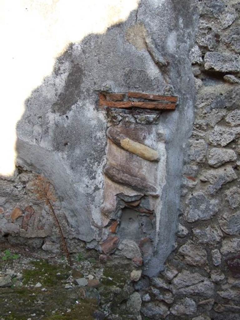 VII.15.13 Pompeii. December 2007. Lararium in kitchen area.
According to Boyce, in the kitchen, located on the east side of the entrance fauces on the east wall above the hearth, was the lararium.
An altar in the form of a low half-column of stucco was applied to the wall and painted red.
Around it coiled a serpent in yellow stucco relief, half of its body in elaborate rings above and to the right of the altar, and actually tied into a knot.
Above the top of the altar “the usual fruits” were reported to have been painted.
On each side was the figure of a Lar.
Below and to the right is painted a tabella ansata, as if meant to contain an inscription, though none was visible at the time of excavation.
The whole painting was bordered by red stripes, and across the top were stretched three garlands.
See Boyce G. K., 1937. Corpus of the Lararia of Pompeii. Rome: MAAR 14, (p.73, no.335, and Pl.23,2). He located this at VII.15.12.
See Giacobello, F., 2008. Larari Pompeiani: Iconografia e culto dei Lari in ambito domestico. Milano: LED Edizioni, (p.195, no.82).