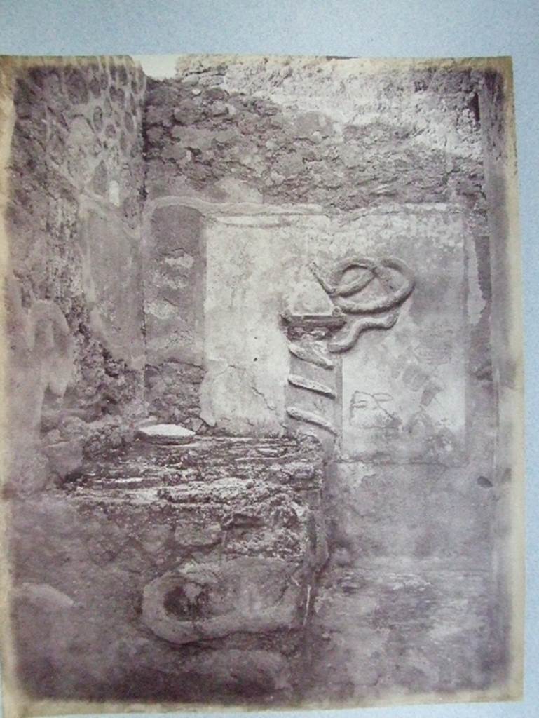 VII.15.13 Pompeii. Kitchen with altar and Genius Lar relief on east wall.
Old undated photograph courtesy of the Society of Antiquaries, Fox Collection. A Lar can be made out in the top left hand corner, and a hog’s head on the right side of the altar.