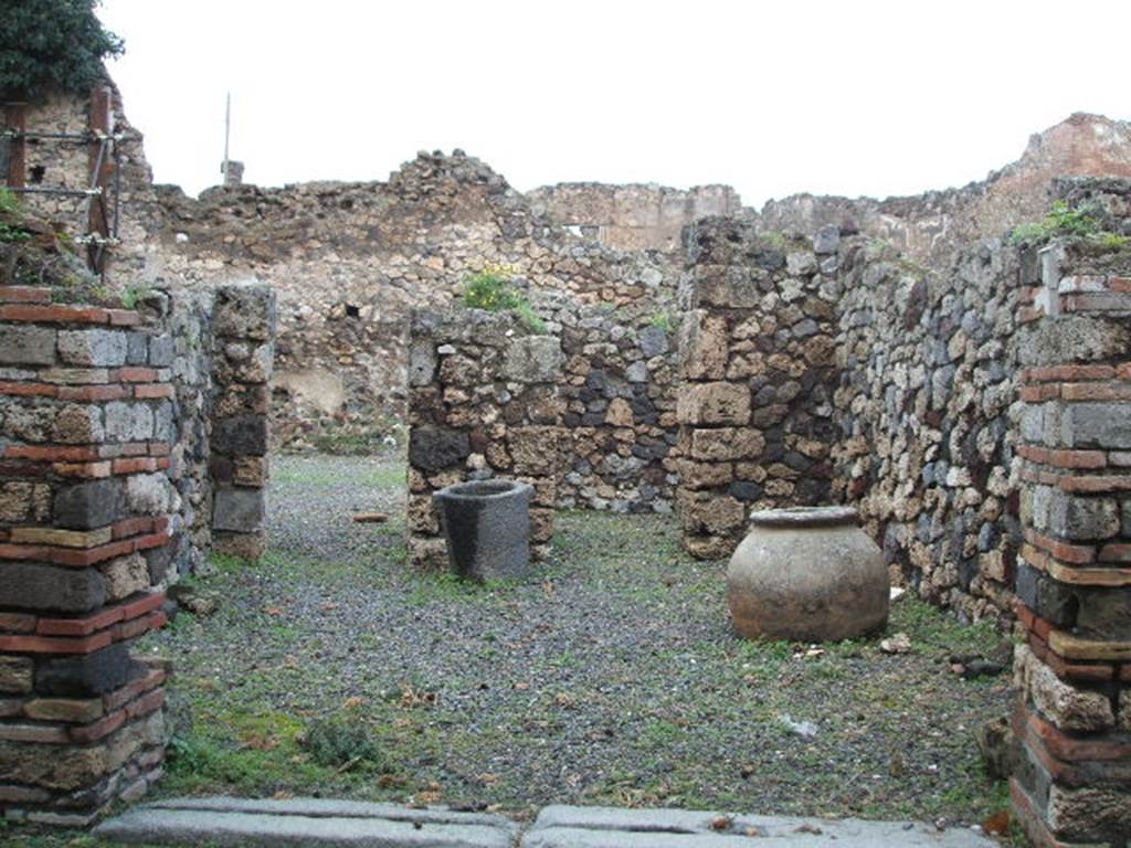 VII.16.4 Pompeii. December 2004. Looking north across shop towards doorway to atrium of VII.16.3, and doorway to rear room.
On the left, in the west wall was another doorway to the entrance corridor of VII.16.3.
According to Boyce –
in the east wall was a semi-circular niche (h.0.40, w.0.45, d.0.20, h. above floor 0.90) – la nicchia dei Penati, according to Fiorelli.
See Boyce G. K., 1937. Corpus of the Lararia of Pompeii. Rome: MAAR 14. (p.73, no.336)
According to Garcia y Garcia, this workshop was destroyed by the bombing of 13th September 1943, and then partially restored in 1950.
There is now no trace of a window at the rear looking into the atrium, as it has been replaced by a doorway.
The niche that Boyce described as being in the east wall, although there was doubt as to its exact position, has not been replaced at all.
Avellino located it in the west wall, whereas Boyce said in the east wall.
See Garcia y Garcia, L., 2006. Danni di guerra a Pompei. Rome: L’Erma di Bretschneider. (p.131)