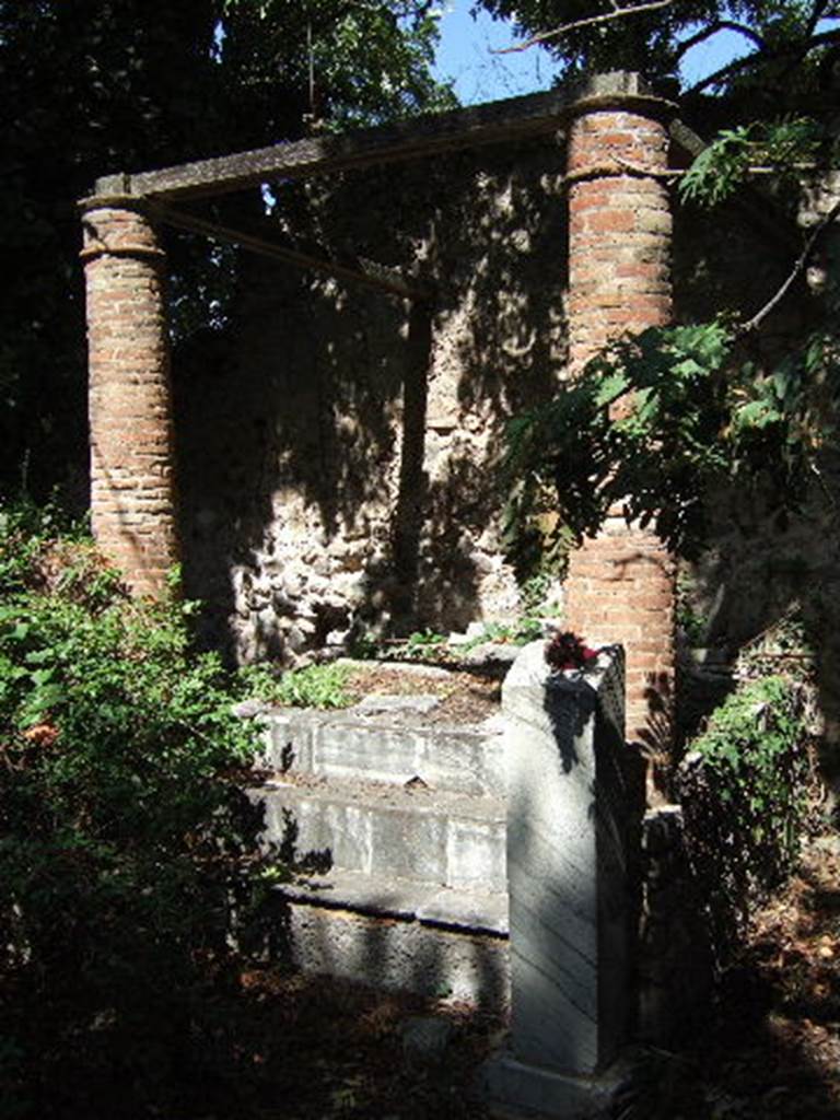 VIII.3.14 Pompeii. September 2005. Garden.
According to Boyce, in the centre of the north wall of the garden stands a large aedicula.
Four steps lead up to the top of the broad, rectangular podium (2.15 by 2.0, h.0.80).
The podium and the steps are covered with marble slabs.
In the centre of the podium stands a ruinous base which supported a marble statue of Diana.
Two columns of brick (h.1.90) supported the front end of the roof over the shrine.
In front of the podium, on each side of the steps, stands a marble base which originally held a herm.
See Boyce G. K., 1937. Corpus of the Lararia of Pompeii. Rome: MAAR 14. (p.75, no.350).