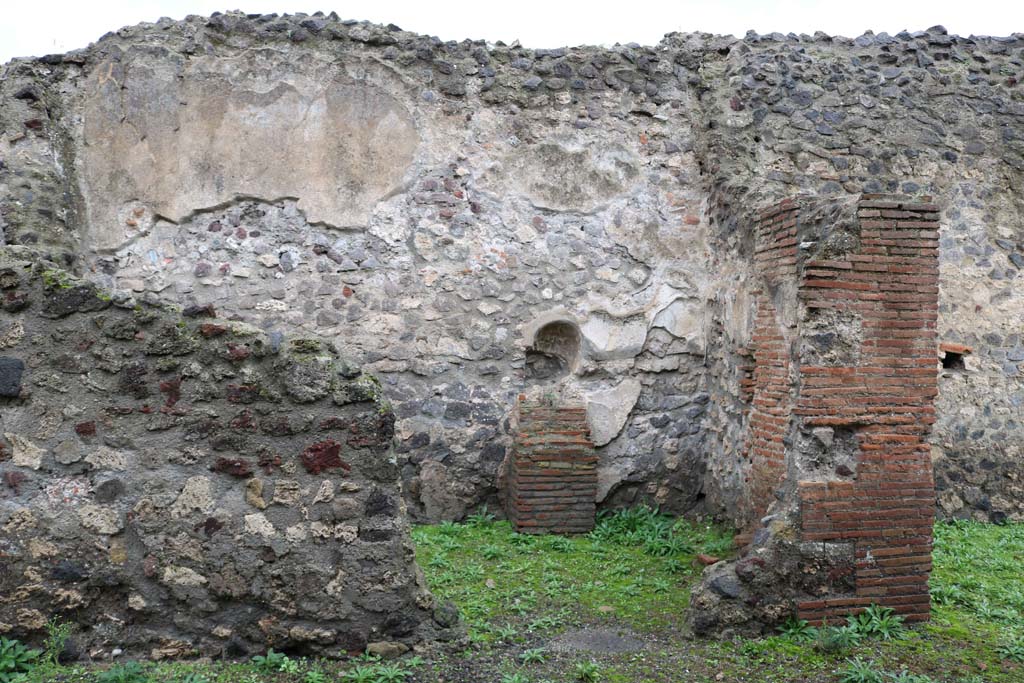 VIII.4.12, Pompeii. December 2018. Looking west into kitchen, room on west of side of tablinum. Photo courtesy of Aude Durand.
According to Boyce, the room on the right of the tablinum may have been the kitchen.
He says in the west wall, pictured above, there was an arched niche.
Its walls were coated with white stucco which was painted with red and yellow flowers.
On the right side of the niche, the lararium painting was painted in two zones.
The lower zone showed a serpent, still visible in 1937, with a red crest and beard, rearing its head above the masonry altar.
The altar was standing against the wall below the niche.
In the upper zone, nothing was visible, but earlier reports described the figure of a Lar painted on the left side of the niche.
On the right side of the niche, there were two painted hams and an eel.
See Boyce G. K., 1937. Corpus of the Lararia of Pompeii. Rome: MAAR 14. (p.76).
See Pappalardo, U., 2001. La Descrizione di Pompei per Giuseppe Fiorelli (1875). Napoli: Massa Editore. (p.128).