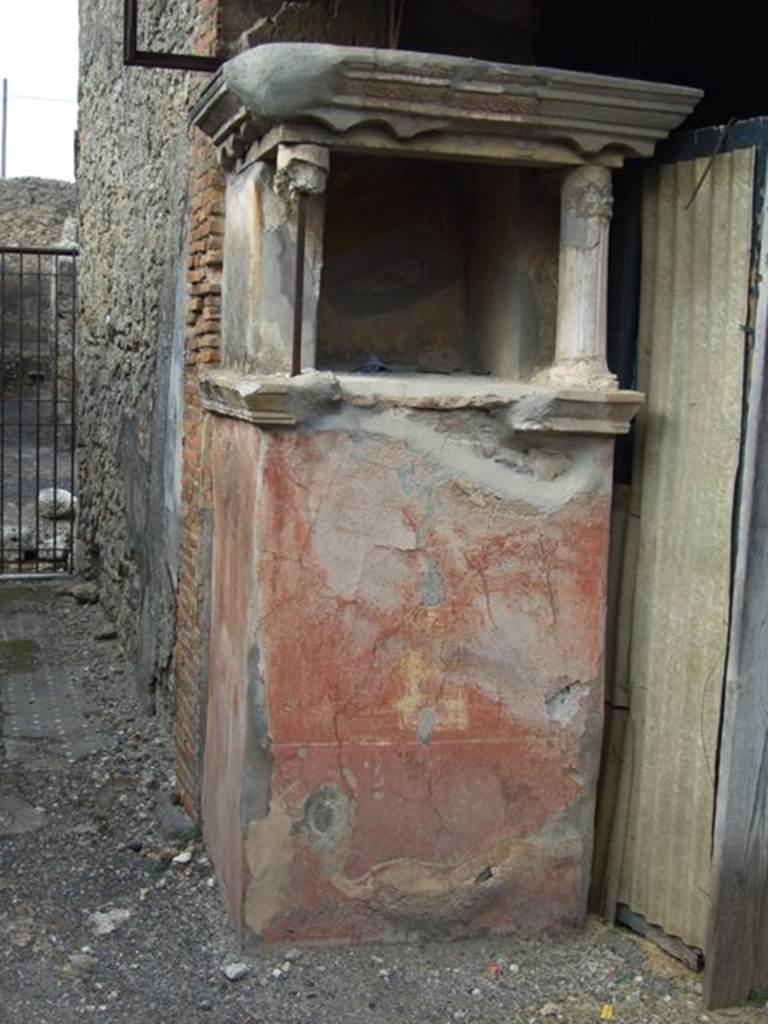 IX.2.26 Pompeii. March 2009. Remains of Lararium.
According to Boyce, the high podium (0.95 by 0.78, h,1.53) was coated with red stucco and on the front was painted a cylindrical altar with offerings.
Two yellowish serpents coiled around the altar, raising their heads to the offerings, one from each side.
Around the top of the podium ran a heavy cornice adorned with a red frieze of stucco, above it two columns.
These columns with capitals and bases (h.0.56) supported an architrave with a design of scallops and a cornice with triple band, all done in coloured stucco.
The back wall was decorated with shrubs and birds painted on a yellow background, the side walls were painted as red and yellow imitation marble.
On the exterior of each side wall were a hippogriff (a mythical beast half griffin and half horse) and two dolphins.
See Boyce G. K., 1937. Corpus of the Lararia of Pompeii. Rome: MAAR 14. (p. 82, no. 404, Pl. 34, 3.)