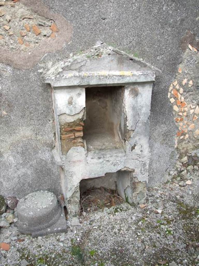 IX.3.15 Pompeii. March 2009. Room 12, aedicula lararium.
According to Boyce, the base (h.0.85 by 0.30, h.0.70) contained a large rectangular recess (h.0.50, w.0.56, d.0.53) coated with white stucco.
Above it the two thick (0.25) side walls support a pediment and with the east wall of the room form a rectangular niche (h.0.65, w.0.35, d.0.60).
In the back wall of the rectangular niche was a semi-circular recess.
The interior was decorated with red spots on a white background.
The tympanum was blue. There were red stripes dividing the exterior of the structure into sections.
This shrine is nowhere mentioned in the excavation reports.
See Boyce G. K., 1937. Corpus of the Lararia of Pompeii. Rome: MAAR 14. (p. 84, no. 414, Pl. 34, 1)