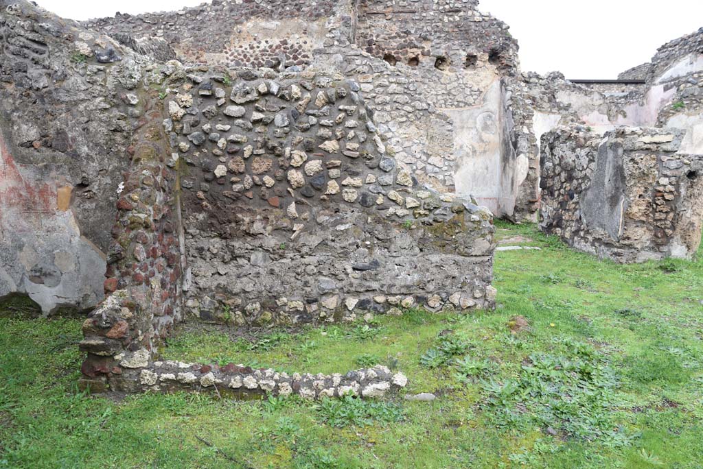 IX.5.18 Pompeii. March 2018. Room “z”, looking north from atrium “b”, with room “g”, on left.
Foto Annette Haug, ERC Grant 681269 DÉCOR.
Zevi considered room “z” may have been a wooden lararium with a marble base.
See Zevi, F., 1964. La Casa Reg IX.5.18-21 a Pompei e le sue pitture: Studi Miscellanei 5. Roma: Bretschneider. (p.11, T: IX,1).
According to Sogliano, found in the second cubiculum on the left side of the peristyle, was the Genio Familiare.
See Sogliano, A., 1879. Le pitture murali campane scoverte negli anni 1867-79. Napoli: (p.10, no.11).
According to Boyce, on the east wall of the cubiculum was a lararium painting, the upper part had fallen.
From a branch of the tree hung a head of a stag.
On the left of the tree, the figure of a small Genius is found, holding in his left, together with the usual cornucopia, a rudder which rested upon a green globe at his feet.
To the left was a small altar, with the serpent gliding towards it. Further to left, was a huge tripod.
On the right stood a male figure, nude except for a green cloak, in his left he held two long spears or poles.
See Boyce G. K., 1937. Corpus of the Lararia of Pompeii. Rome: MAAR 14. (p.86, no.427).