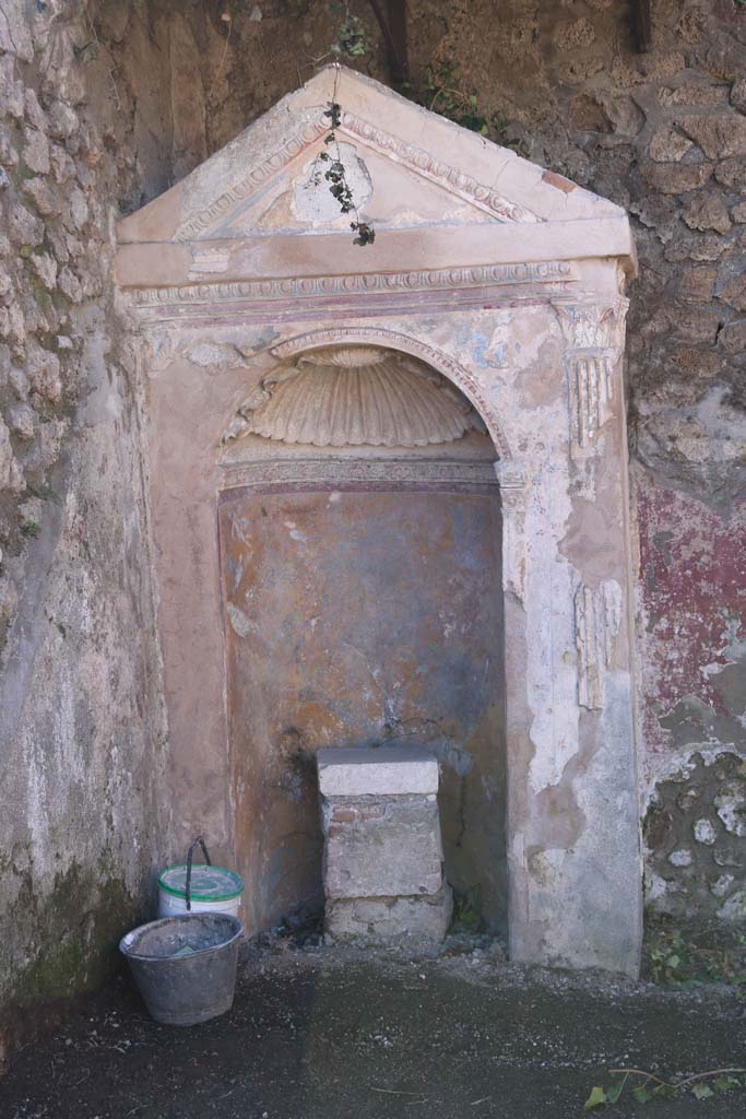 IX.6.8 Pompeii. February 2020.
Aedicula lararium in garden area 9. Photo courtesy of Aude Durand.
According to Boyce –
In the south-west corner of the garden area stands an aedicula – a rectangular masonry structure (1.36 by 0.67, h.2.65) with gable roof.
The front side is ornamented with an aedicula façade surrounding the opening of an arched, semicircular niche.
There is no podium, for the niche extends to the floor. ………….
The interior of the niche is coated with yellow stucco, and upon it are painted a leafy tree with birds flying about it, and on each side, Cupids and marine monsters. The vaulted ceiling is ornamented with a stucco shell.
On the floor within the niche, stands a rectangular base, apparently intended to support a statue; it is coated with stucco and upon the front side a mask is painted. …………..
He references – Not. Scavi, 1880, 231; Bull. Inst., 1882, 116.
See Boyce G. K., 1937. Corpus of the Lararia of Pompeii. Rome: MAAR 14. (p.87, no.432).
See Giacobello, F., 2008. Larari Pompeiani: Iconografia e culto dei Lari in ambito domestico. Milano: LED Edizioni, (p.286 no.V81)