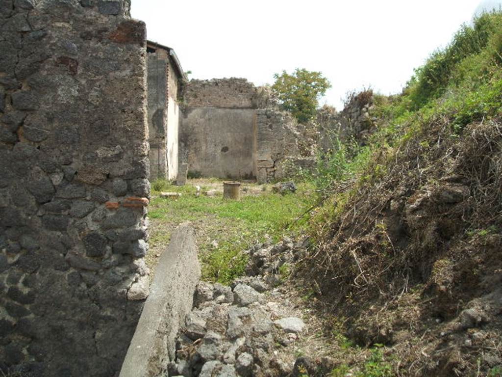 IX.8.c Pompeii. May 2005. Looking east from entrance doorway.
According to Boyce –
In the west wall of the kitchen, reached from the south side of the peristyle, was a rectangular niche (h.0.44, w.0.65, d.0.26, h. above floor 1.0). On the wall above it was a lararium painting. (See description in Paintings).
See Boyce G. K., 1937. Corpus of the Lararia of Pompeii. Rome: MAAR 14. (p.90, no.452).