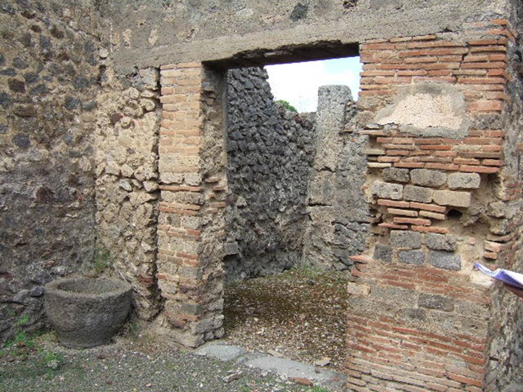 IX.9.6 Pompeii. May 2006. Doorway to cubiculum in north-west corner of atrium.
According to NdS, the doorway to this room was made narrower by the addition of a pilaster formed by rows of masonry bricks and tufa cut in a similar style, on its left. When found, this doorway was furnished with a door, the imprint of which could be seen at the time of excavation, but it could not be saved. The room had a rough signinum floor, and rustic walls. In the west wall was a semicircular niche, plastered entirely in white stucco studded with coloured specks, which could have been flowers. In this room, some amphorae were found (see NdS, 1887, p.561) containing lime. In the rustic plaster, on the pilaster between the entrance corridor and the doorway to the room (right in picture above), graffiti were found. They read –
IVCVNDVS and QVOIVS
VIINVS LABORE
VITALIS
See Notizie degli Scavi, 1889, p.123.