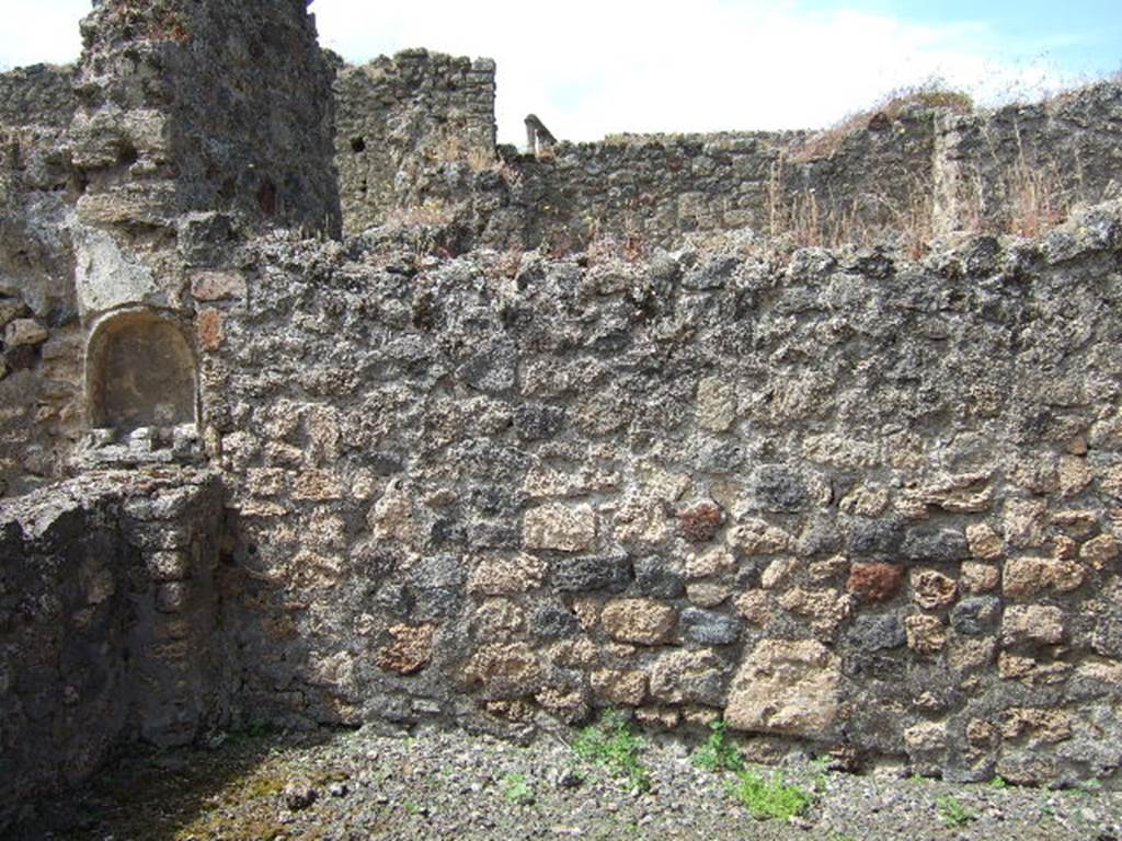 IX.9.6 Pompeii. May 2006. West wall of wide portico, with lararium niche.
This portico was supported by two pillars, by a masonry arch and a long architrave.
The portico had rustic walls with a high black zoccolo/plinth, which, however, was not continuous: in the west wall, and really in the vertical wall from which the arch originated, a semicircular niche covered in white plaster was hollowed out. Underneath of which, was a matching masonry altar, leaning against the wall and parapet of the inter-columnisation.
See Notizie degli Scavi di Antichità, 1889, p.123.