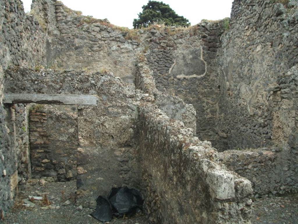 IX.9.9 Pompeii. May 2005. Looking south from corridor, towards doorway to light-yard (seen on upper right side). Through the doorway on the left, was an open courtyard garden area at the south of the corridor. At the rear of the doorway (on upper left-side) would be another room with a doorway from the open courtyard and with window into the courtyard on its west side. According to Eschebach, on the right was a kitchen with a window to the light-yard. At the rear was a windowed triclinium, and a courtyard garden.
See Eschebach, L., 1993. Gebäudeverzeichnis und Stadtplan der antiken Stadt Pompeji. Köln: Böhlau. (p.442)
According to NdS, the room on the right would have been a narrow storeroom. The room in the upper left-rear side was a “mystery” room (stanza mistica) with a projecting window into the courtyard. In the courtyard was the doorway to the “mystery” room, on its external wall was seen the remains of a painting of a large serpent. In its north-west corner, and bricked into the pilaster, was a terracotta tub or basin ?
See Notizie degli Scavi, 1889, p.526