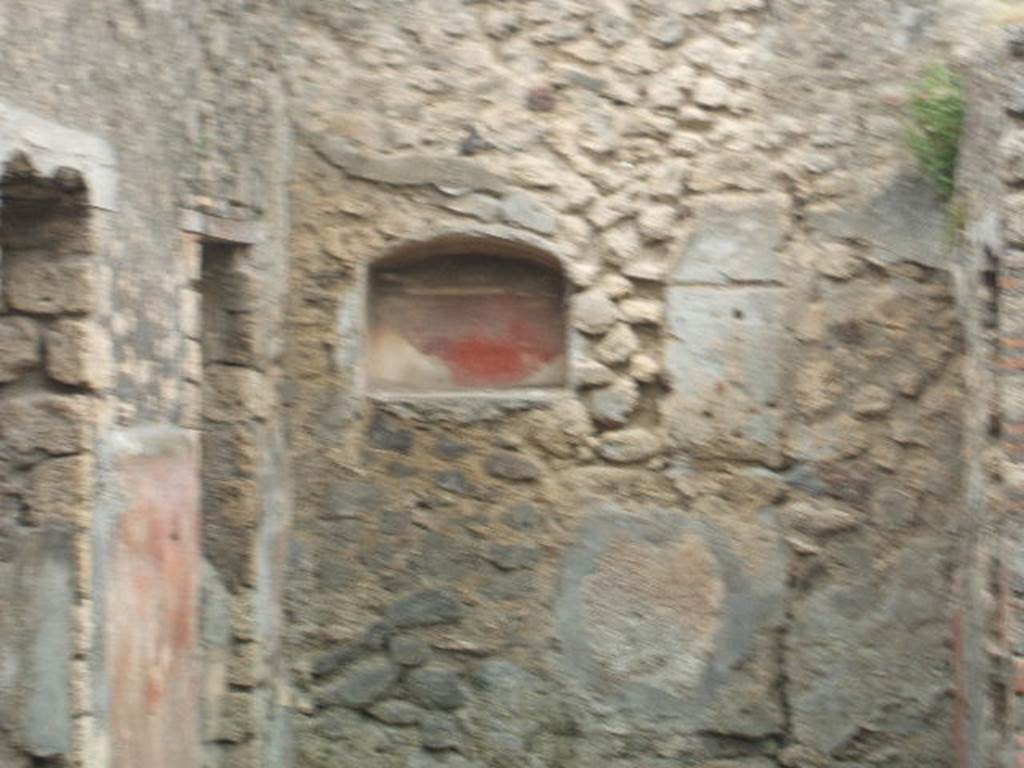 IX.9.13 Pompeii. May 2005. Room 6, arched niche set in west wall in south-west corner of garden.
According to Boyce –
On the wall to the right of the niche was the lararium painting: on the left stands a tripod of unusual form with a dark coloured vessel upon it. The Genius, standing to the right, pours a libation upon the tripod; he wears a wreath of leaves; the toga does not seem to be drawn over hs head as usual, though the preservation of the painting is poor at this point; he holds no cornucopia. Behind and to the right stand two figures: in the first plane, a camillus, also wreathed, and carrying fruit in a shallow dish; above and farther right, a popa, wreathed and carrying an axe.
To the left of the Genius are two wreathed figures apparently women, though it is impossible to be certain, for only the upper portions of their figures are preserved.
On the left side of the niche there was not room for painted figures, but on the adjoining south wall the figure of the Genius appears again, clad in white toga and pouring a libation upon a yellow cylindrical altar with a fire; he is unbearded, his flesh is reddish, and in is left hand he holds a yellow cornucopia.
This double Genius certainly has some special significance. …….
See Boyce G. K., 1937. Corpus of the Lararia of Pompeii. Rome: MAAR 14. (p. 93, no. 466).
See Notizie degli Scavi di Antichità, 1891, p. 258
See Jashemski, W. F., 1993. The Gardens of Pompeii, Volume II: Appendices. New York: Caratzas. (p. 247)