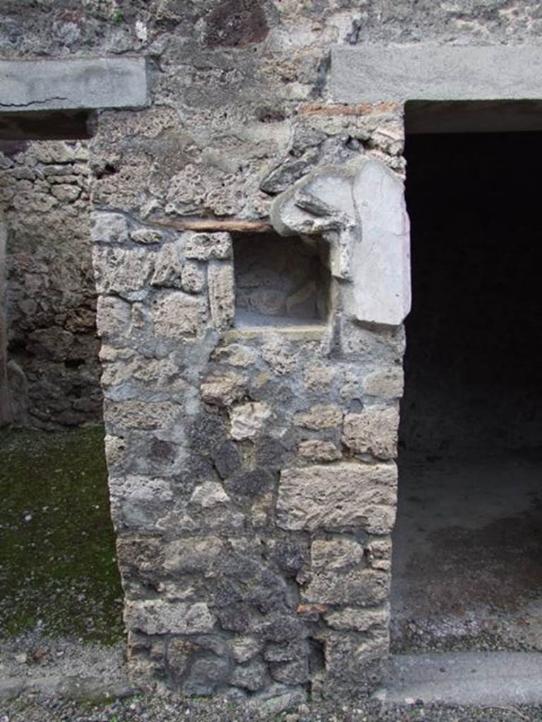 IX.9.c Pompeii. March 2009. North wall of north-west corner of portico.
According to Boyce –
in the pillar that separates two doorways on the north side of the peristyle was a rectangular niche (h.0.30, w.0.28, d.0.20, h. above floor 1.38).
The niche was adorned with a stucco aedicula façade which consisted of two half-columns supporting a pediment.
In the tympanum was a patera upon a bluish background.
Also according to Boyce, a bronze figure of Hygeia seated upon a throne with her feet upon a footstool, was found in a room to the left of the fauces.
On each side of the throne stood a small tree, around which coiled a serpent.
See Boyce G. K., 1937. Corpus of the Lararia of Pompeii. Rome: MAAR 14. (p. 93, no. 467, and Note 4).
Giacobello described it as a pseudo-aedicula lararium.
See Giacobello, F., 2008. Larari Pompeiani: Iconografia e culto dei Lari in ambito domestico. Milano: LED Edizioni, (p.287 no.V85)