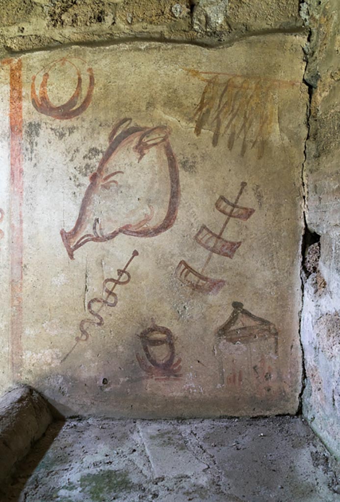 IX.9.c Pompeii. March 2023.
East end of north wall of kitchen, wall painting of hanging birds, ring sausages, a pig’s head and meat on a stick.
Photo courtesy of Johannes Eber.