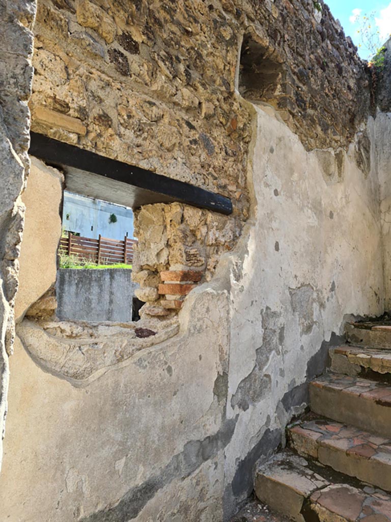 Villa of Diomedes, Pompeii. May 2024.
East wall at side of stairs, with lararium niche in upper wall with window below. Photo courtesy of Klaus Heese.
According to Boyce,
Just to the right of the main entrance six steps lead down to the servants’ quarters, and in the wall beside this stair is a piccolo larario – apparently only a niche, in which a statuette of Minerva was found.
See Boyce G. K., 1937. Corpus of the Lararia of Pompeii. Rome: MAAR 14, (p.97, no.476).
See Giacobello, F., 2008. Larari Pompeiani: Iconografia e culto dei Lari in ambito domestico. Milano: LED Edizioni, (p.221, no.3)