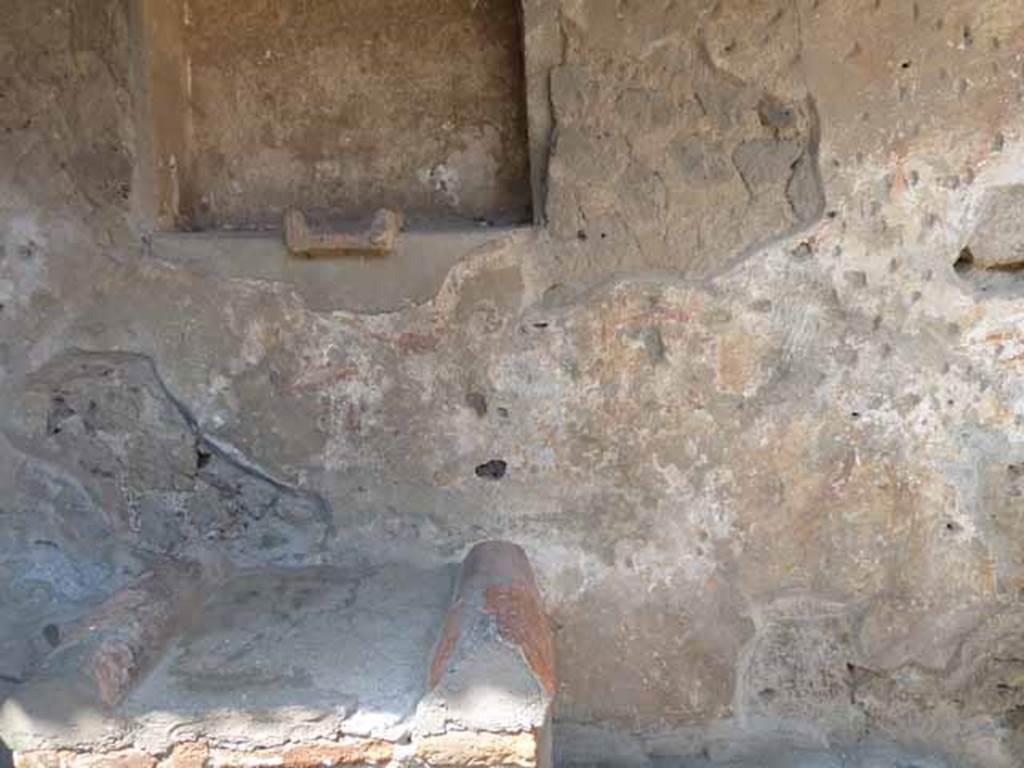 Villa of Mysteries, Pompeii. May 2010. Room 61, north wall of kitchen courtyard near lararium. According to Boyce in 1937, the last layer of plaster had already fallen revealing an earlier layer beneath it, decorated with a figure painting in red and yellow. Maiuri concluded that this was a fragment of the pre-Roman art of the house shrine. When excavated, the paintings were very poorly preserved, and had almost disappeared by 1937. The following description was written by De Petra in Not.Scav, 1910, 141: “Below and to the right of the niche is represented a procession made up of two horsemen, a crowd of people and a tibicen who approaches the altar in the centre, coming from the left. To the right of the same altar are a Camillus and a second figure. A still more ancient layer of plaster shows on the right of the niche a strange figure like a Lar pouring from a rhyton of curious shape into a patera (?) held in the other hand; on each side of him are garlands”.
See Boyce G. K., 1937. Corpus of the Lararia of Pompeii. Rome: MAAR 14. (p.97)
See Maiuri, Villa dei Misteri, 80, and fig. 32.