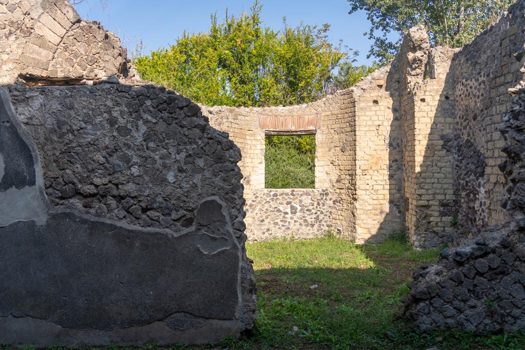 Villa of Mysteries, Pompeii. October 2023.
Room 26, at front, looking into room 25, apsidal hall at rear. Photo courtesy of Johannes Eber.
According to Boyce –
In a room opening off the north-west corner of large peristyle is a room of curious shape with an apse in the side opposite the entrance door, and four rectangular niches in the walls. It was undergoing renovation at the time of the eruption designed to make it a finer room that before.
Maiuri thought it may have been intended as a domestic Sacellum, and possibly would have housed the statue of Livia found nearby in the peristyle.
See Boyce G. K., 1937. Corpus of the Lararia of Pompeii. Rome: MAAR 14. (p. 98, no. 484).
See Maiuri, 1967 Ed. Villa dei Misteri, (76 and fig.29)