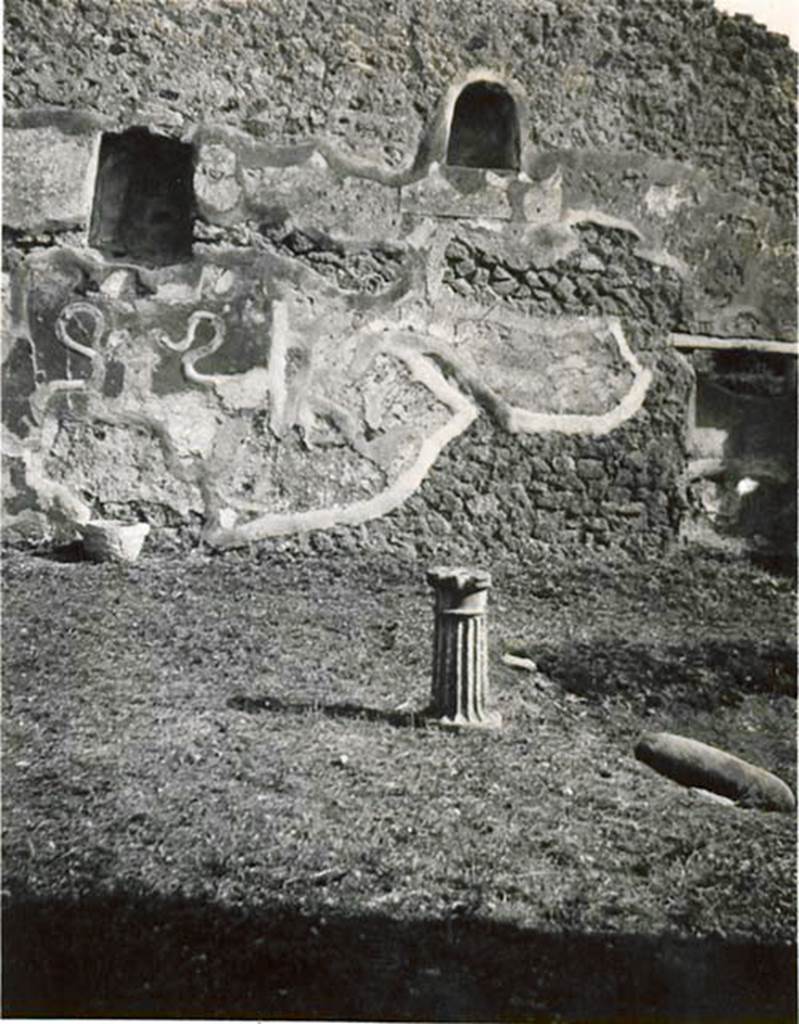 I.2.3 Pompeii. 1935 photo by Tatiana Warscher. Looking towards the south wall of the atrium, with a single table-leg in the centre. In the south wall are a cupboard/recess and two niches for the household Lares, underneath can be seen the two serpents coiling around an altar, in stucco relief. Warscher described the atrium as –
“I.2.3, l’atrio con un monopodio in mezzo. Nella parete sud – sono un armadio e due nicchie per i Lari, sotto una delle quali sono effigiati in stucco a rilievo i due serpenti.
See Warscher T., 1935. Codex Topographicus Pompeianus: Regio I.2. (no.2), Rome: DAIR, whose copyright it remains.