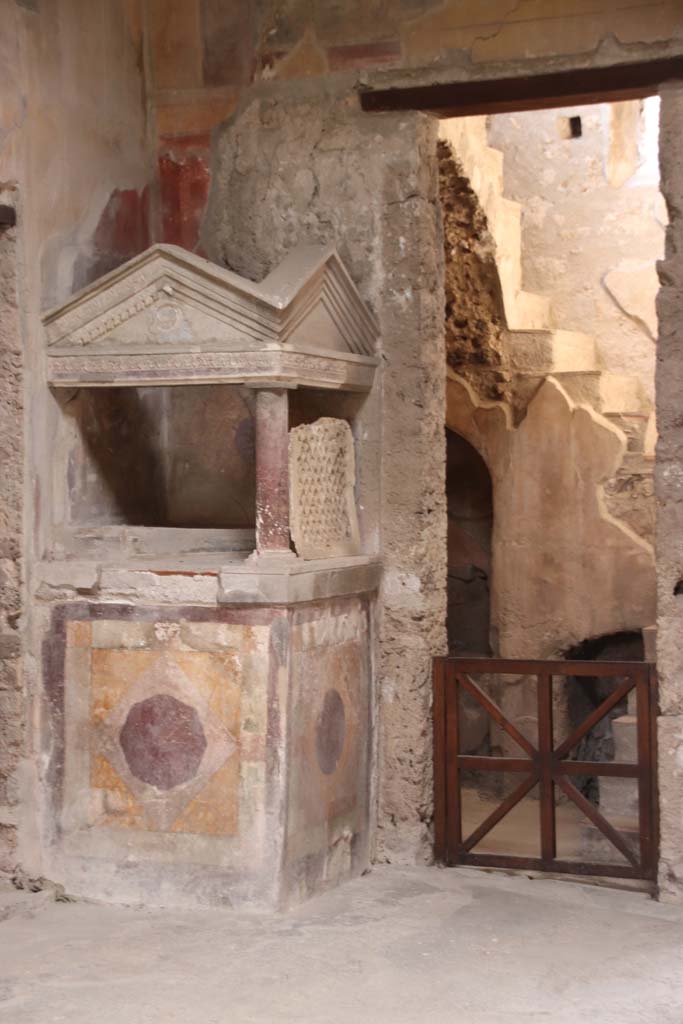 I.10.4 Pompeii. September 2021.
Looking towards north-west corner of atrium, the lararium and doorway to room 2.
Photo courtesy of Klaus Heese.
According to Boyce –
A masonry podium (1.08 square, h.1.35) is built into the corner, and above it rises a little temple, formed by a single column at the one free corner of the podium, supporting a roof of two pediments. ………..
See Boyce G. K., 1937. Corpus of the Lararia of Pompeii. Rome: MAAR 14. (p.27-28, no.48).