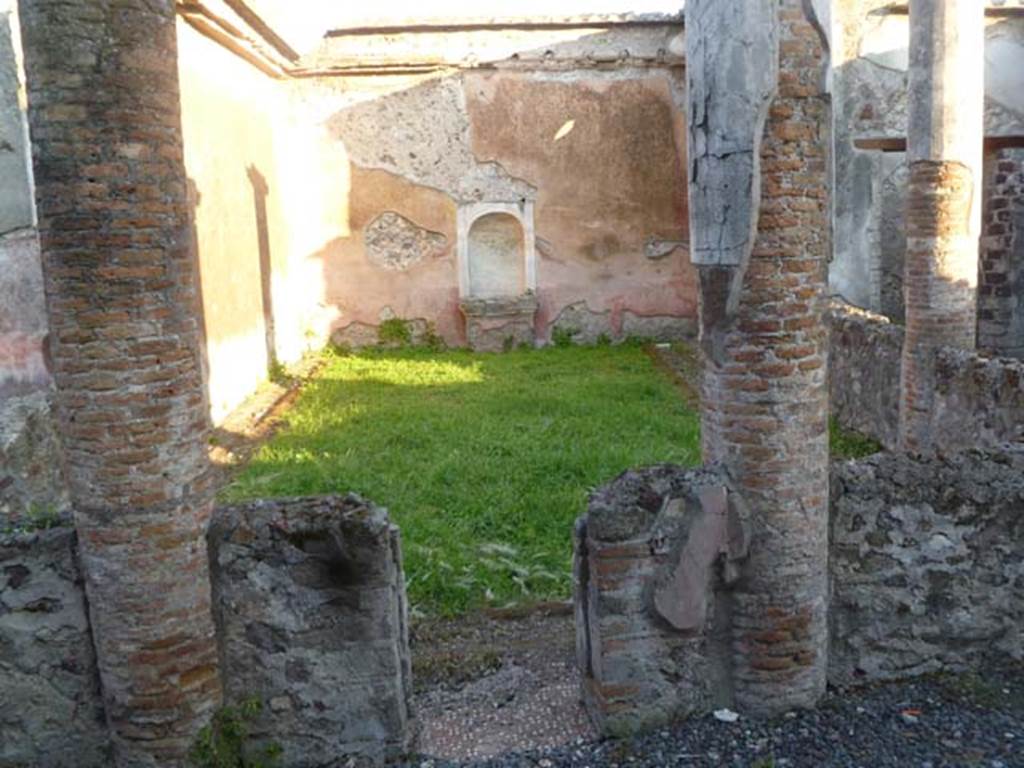 VI.2.22 Pompeii. May 2011. Looking south from north portico.
According to Boyce, standing in the centre of the south wall is a fine aedicula lararium (h.2.55).
Upon a rectangular base, painted red, a heavy projecting ledge adorned with triple bands of stucco ornament supports a platform (1.10 x 0.35, height above the floor 0.75), upon which rest the bases of two tall, fluted columns (h.1.30) with bases and capitals – all coated with white stucco.
The columns in turn support a pediment, the tympanum of which is surrounded by a double cornice of stucco relief.
The back wall within the aedicula is hollowed out to form a shallow semi-circular niche, and painted blue.
See Boyce G. K., 1937. Corpus of the Lararia of Pompeii. Rome: MAAR 14, (p.44, no.142, Pl.5,2)
See Giacobello, F., 2008. Larari Pompeiani: Iconografia e culto dei Lari in ambito domestico. Milano: LED Edizioni, (p.269 no.V41)