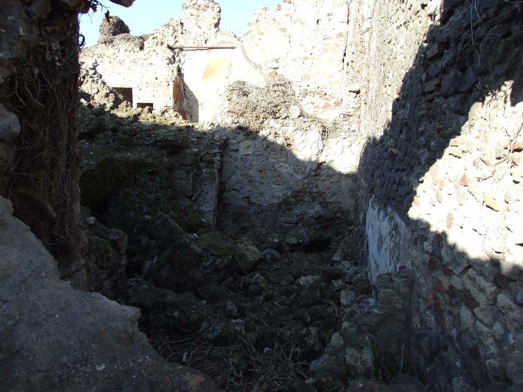 VI.14.39 in foreground, looking north into rear rooms, (“l” (L) and “m”) taken from VI.14.22. December 2007.
These may have originally been underground rooms, the kitchen and wine cellar.
In the background is a room at the east (rear) of the peristyle of VI.14.38.
According to Boyce, on the east wall of the subterranean kitchen of VI.14.39, was a lararium painting in two zones.
The upper zone contained a sacrificial scene with the Genius on the right of an altar.
On the left was a Camillus, wreathed and wearing a short, girded tunic.
On each side of this group stood a wreathed Lar, carrying rhyton and situla.
In the lower zone, to the right of an altar furnished with an egg, was a red serpent with large crest and beard.
Behind the serpent, at the extreme right of the painting, was a jar.
On the left of the altar some other indistinguishable object, seems to have replaced the second serpent.
Across the top of the upper zone was stretched a garland, and in the background between the figures were painted plants.
See Boyce G. K., 1937. Corpus of the Lararia of Pompeii. Rome: MAAR 14. (p.53, no. 206)
See Sogliano, A., 1879. Le pitture murali campane scoverte negli anni 1867-79. Napoli: (p. 13, no. 28)
See Giacobello, F., 2008. Larari Pompeiani: Iconografia e culto dei Lari in ambito domestico. Milano: LED Edizioni, (p.179, no.61, for a description of the lararium, no longer conserved in the underground kitchen, due to the house being badly damaged in 1943 bombing).