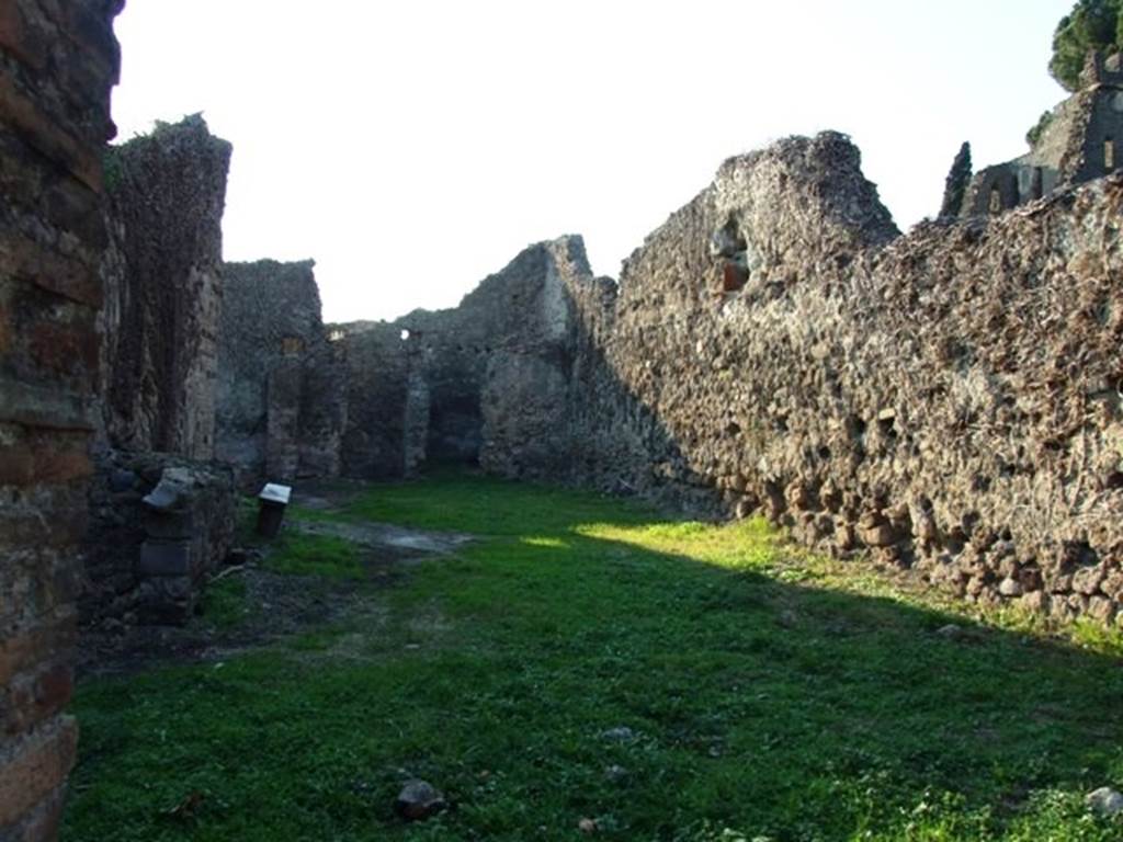 VI.15.18 Pompeii. December 2007. Looking west from entrance.
According to Boyce, this was an irregular building which was undergoing alterations at the time of the eruption. Its purpose was not clear, perhaps the large central room was used for housing carts. The walls seem to have been all undecorated except for those in a long narrow room in the south-west corner. In the south end of that room, a domestic sacellum was built. The sacellum had a vaulted ceiling and a floor of pounded sherds, and according to Mau dated from the period of the First Style. Against the south wall stood a masonry altar with concave upper surface. It was coated with white stucco and upon its front side was painted a small flaming altar with a large serpent on each side. Near to it on the east wall was a small niche, on the white background of the rear wall was a painted figure. The figure was clad in a blue garment and reclining upon a couch. The rear and side walls of the niche were adorned with painted red leaves and three quinces.
In the room to the north, through which access to this sacellum was gained, on the east wall was a rectangular panel of white stucco.
Within the panel was set a tiny niche for a lamp. Above the panel of white stucco was a second niche coated with coarse plaster and having a painting done in red, on the rear wall. This painting was very poorly preserved but seemed to represent an aedicula and within it an altar.
Not. Scavi, 1897, 463, photograph p.464. See Boyce G. K., 1937. Corpus of the Lararia of Pompeii. Rome: MAAR 14.(p.56, no.218)