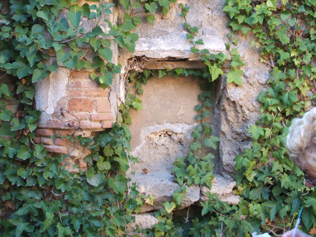 VII.2.51 Pompeii. December 2004. Niche in west wall of viridarium with half column at side.
According to Boyce –
this square niche (h.0.50 square, d.0.30, h. above floor 1.45) in the west wall of the pseudo-peristyle had a projecting cornice beneath it.
Its inside walls were coated with red stucco.
See Boyce G. K., 1937. Corpus of the Lararia of Pompeii. Rome: MAAR 14. (p. 63 no. 256).