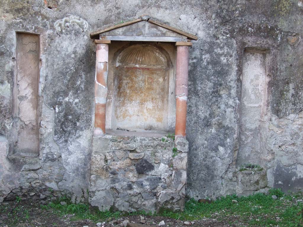 VII.3.6 Pompeii. December 2006. Aedicula lararium against south wall of garden area.
According to Boyce –
above a rectangular podium (1.05 by 0.50, height 0.95) stand two columns (h. 1.0) coated with red stucco.
These supported the roof with pediment.
The semi-circular niche in the rear wall had its vaulted ceiling adorned with a stucco shell.
The walls of the niche were painted orange and on each side of the niche was a stucco pilaster.
A large marble statuette of Venus Anadyomene (H.0.72) was found in the aedicula.
On either side of the aedicula are two long vertical slits, Fiorelli suggested they may have held candelabra.
See Boyce G. K., 1937. Corpus of the Lararia of Pompeii. Rome: MAAR 14. (p. 63, no: 259 and pl. 36, 1).
See Giacobello, F., 2008. Larari Pompeiani: Iconografia e culto dei Lari in ambito domestico. Milano: LED Edizioni, (p.280 no.V64)