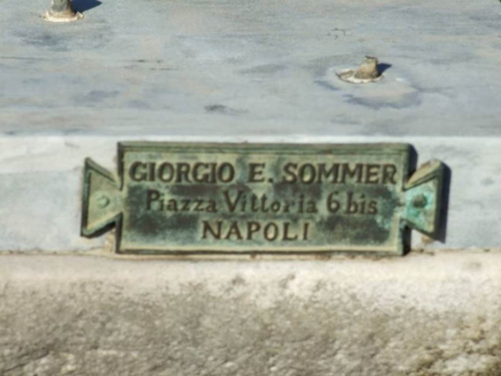 V.1.7 Pompeii. December 2007. Room 1, atrium. Pedestal on impluvium where a replica of the bronze bull, made by Sommer to replace the original, stood.
Plaque with name of Giorgio E. Sommer of Piazza Vittoria 6 bis NAPOLI records this.
In addition to his photography business, Sommer also had a bronze casting business, making replicas of items in museums and the excavations.