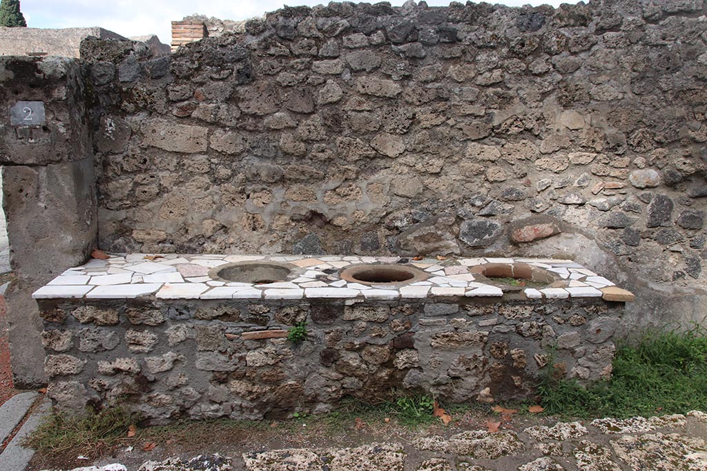 I.1.2 Pompeii, October 2024. Looking towards north wall and counter containing three clay urns. Photo courtesy of Klaus Heese.