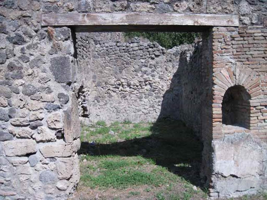 I.1.2 Pompeii. September 2010.
Doorway to rear room "b" in north-east corner, perhaps for the use of customers.
Looking east. Photo courtesy of Drew Baker.
According to Warscher, quoting Mau in Bull. Inst 1875, p.26,
“Dietro alla bottega a destra vi è la spaziosa cucina con focolare e cesso, a sinistra una stanza larga 2,96, profonda 5,24, dipinta negligentemente nello stile degli ultimi tempi di Pompei: i colori predominanti sono rosso nello zoccolo, giallo nella parte media, bianco in quella superiore.
Sul muro di S troviamo un quadro alto 0,30, largo 0,40, rappresentante la morte di Elle. Il fondo è tutto riempito di color turchino che rappresenta il mare. Sull’ariete che corre verso destra, sta seduto Frisso, rivolto allo spettatore e la coscia destra, come pare, coperta d’una veste bianca, tenendosi colla sinistra al collo dell’ariete, mentre stende la destra ad Elle, che dietro l’ariete affonda nel mare, alzando verso il fratello ambedue le mani.
Sul muro di E un altro quadro molto mal conservato, alto 0,38, ed altrettanto largo, ci mostra Apolline ritto in piede e rivolto a sinistra, verso la qual parte stende la man destra, mentre sopra la spalla sinistra molto svanita ma con sufficiente vertezza si scorge la lira. La posizione elevata della lira ed il confronto delle pitture 180 e 201 (helbig) ci lasciano supporre, che essa fosse appoggiata sopra una base o un pilastro. Dal movimento del braccio destro si potrà conghietturare, che nella parte sinistra del quadro fosse ancora un’altra figura, alla quale il deo si rivolgesse”.
See Warscher T., 1936. Codex Topographicus Pompeianus: Regio I.1, I.5. Rome: DAIR, whose copyright it remains. (a, dopo no.11)
(translation:
Behind the shop to the right there was the spacious kitchen with hearth and toilet, to the left a room 2,96 wide, by 5,24 deep, carelessly painted in the style of the last days of Pompeii: the predominant colours were red on the zoccolo, yellow in the middle part, white at the top. On the south wall, a painting of the death of Helle, O,30 high, 0,40 wide, could be seen. The bottom was all filled with blue color representing the sea.
On the ram that moved to the right sat Phrixus, facing to the viewer and the right thigh, as it seemed, covered in a white robe, keeping his left hand around the neck of the ram, while extending the right hand to Helle, who behind the ram sinks into the sea, raising both hands to her brother. On the east wall, there was another picture very poorly preserved, 0,38 high, and equally wide, showing Apollo standing and turned to the left, extending his right hand, whilst over the left shoulder, very faded but with sufficient to perceive the lyre. The elevated position of the lira and the comparison of paintings 180 and 201 (Helbig) suggested that it was placed above a base or a pillar. By the movement of his right arm, which may be conjectural that on the left side of the picture was yet another figure, to whom the god turned. The execution of both paintings as far as the bad conservation allows us to judge, seemed rather neglected, by the fact that they were overlapping onto the yellow of the wall, whether to execute a painting with greater diligence for the most, or put fresh plaster on after you finish the decorative part of the wall, or at least leave space for it."