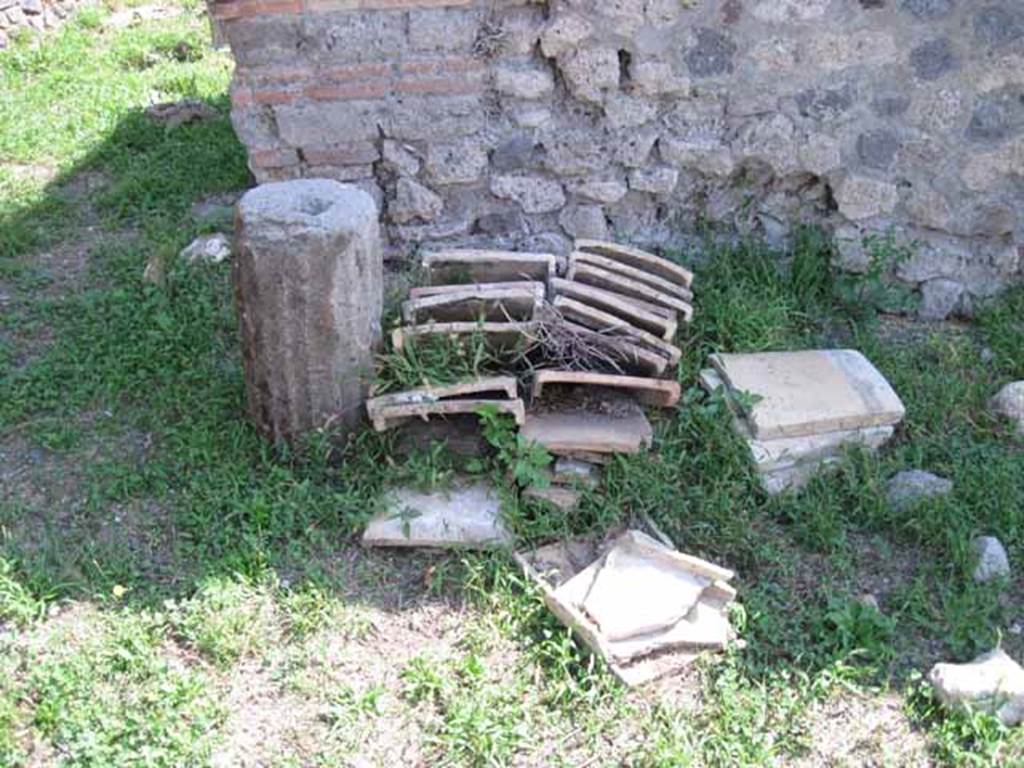 I.1.3 Pompeii. September 2010. Detail of column drum and roof tile deposit on south wall of yard area. Photo courtesy of Drew Baker.