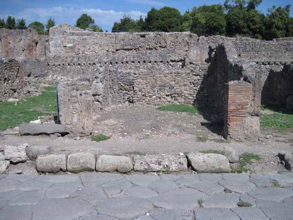 I.1.6 Pompeii. September 2010. Looking east towards entrance on Via Stabiana. Photo courtesy of Drew Baker.
According to Warscher, quoting Mau in Bull.Inst 1875, p.30, I.1.6-9: “Segue un altro albergo, molto simile a questo descritto. Qui pure è interrotto il marciapiede per lasciar entrare i legni. L’entrata era chiuse mediante una porta a quattro partiti, congiunti a due adue, come si conosce dai quattro buchi per i chiavistelli. Qui pure si entra prima in un compreso che ha le dimensioni d’una bottega grande con una dietrobottega e posteriormente si apre sopra una grande corte, lungo il cui muro di fondo qui pure si stende la stalla, larga 13,30, profonda 2,47 con una finestra sul vico settentrionale e due porte, una all’estremità meridionale, l’altra poco distante da quella settentrionale.
Presso a quest’ultima una parte della corte è selciata. Lungo il muro N vi sono due camere con finestre sul medesimo vico, e prossimo alla stalla il cesso. Si vede anche il cesso del piano superiore e i tubi di mattone d’un terzo, che stava ancora più in alto.
Nell’angolo NO vi sono I primi gradini d’una scala, la cui parte superiore sarà stata di legno, in quello SO l’apertura della cisterna, e accanto nella stessa massa di materiale una vasca lunga stretta e bassa, come quella sudescritta nella casa adiacente.
Qui la vediamo frapposto fra la cisterna ed il muro di O, il che esclude categoricamente l’aver essa servito d’abbeveratoio. Dalla parte più bassa di essa, aperta come nella casa sudescritta, l’acqua colava in un’altra vasca larga 1,02 x 1,54, di cui un lato viene formato dalla suddetta massa di fabbrica, uno dal muro occidentale, i due rimanenti da appositi muricciuoli. Essa ha al fondo uno scolo verso N, che dà in un vaso ossia tubo di mattone, incastrato nel suolo. Nella parete vi era la pittura dei Lari, di cui sono rimasti soltanto i serpi. A destra dell’ingresso per i legni sta un locale come una bottega.
L’essere esso congiunto mediante una porta con quel primo compreso, ove entravano i legni, ci lascia supporre, aver esso servito di caupona per i vetturini”.
See Warscher T., 1935. Codex Topographicus Pompeianus: Regio I.1/I.5. Rome: DAIR. (no.14)
(translation: “I.1.6-9: Followed another hotel, very similar to this. Here also the pavement was interrupted to allow entry for the “carts?”/the wood?. The entrance was closed by a door of four entries, joined two by two, as you knew from the four holes for the bolts. Here we entered first into a complex that had the dimensions of a large shop with a rear-room and behind, it opened onto a large courtyard, along whose rear wall was the stable, l3,30 wide, 2,47 deep, with a window onto the northern roadway and two doorways, one at the extreme southern end, the other not far from the north. Near to this last, a part of the courtyard was paved. Along the north wall there were two rooms with windows onto the same roadway, and the toilet was next to the stables. Also, you could see the toilet on the upper floor and the brick pipes of a third, who was even higher still. In the north-west corner , there were the first steps of a staircase, the upper part would have been of wood, in the south-west was the opening of the cistern, and nearby in the same mass of material there was a long narrow and low basin, the same as that described in the adjacent house. Here we see it came between the cistern and the west wall, which excluded categorically that it was used as a drinking trough. From the lower part of it, open as in the described house, water strained into another large basin 1,02 x 1,54, one side of which was formed by that mass of masonry, one from the western wall, the two remaining from suitable low walls. It had at the bottom a drain to the north, which went into a jar or brick (terracotta?) pipe, buried in the ground. On the wall there was the painting of the Lares, of which only the serpents remained. To the right of the entrance for the carts, was a room like a shop. This was connected through a door with that first area, where the carts entered,