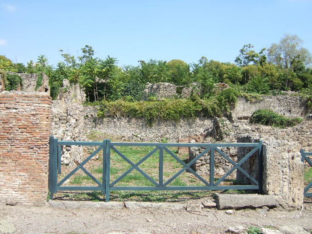 I.1.8 Pompeii, on left, and I.1.7 Pompeii, stairs to upper floor, on right. September 2005.
According to Warscher, quoting Mau in Bull.Inst 1875, p.30, I.1.6-9: “Segue un altro albergo, molto simile a questo descritto. Qui pure è interrotto il marciapiede per lasciar entrare i legni. L’entrata era chiuse mediante una porta a quattro partiti, congiunti a due adue, come si conosce dai quattro buchi per i chiavistelli. Qui pure si entra prima in un compreso che ha le dimensioni d’una bottega grande con una dietrobottega e posteriormente si apre sopra una grande corte, lungo il cui muro di fondo qui pure si stende la stalla, larga 13,30, profonda 2,47 con una finestra sul vico settentrionale e due porte, una all’estremità meridionale, l’altra poco distante da quella settentrionale.
Presso a quest’ultima una parte della corte è selciata. Lungo il muro N vi sono due camere con finestre sul medesimo vico, e prossimo alla stalla il cesso. Si vede anche il cesso del piano superiore e i tubi di mattone d’un terzo, che stava ancora più in alto.
Nell’angolo NO vi sono I primi gradini d’una scala, la cui parte superiore sarà stata di legno, in quello SO l’apertura della cisterna, e accanto nella stessa massa di materiale una vasca lunga stretta e bassa, come quella sudescritta nella casa adiacente. Qui la vediamo frapposto fra la cisterna ed il muro di O, il che esclude categoricamente l’aver essa servito d’abbeveratoio. Dalla parte più bassa di essa, aperta come nella casa sudescritta, l’acqua colava in un’altra vasca larga 1,02 x 1,54, di cui un lato viene formato dalla suddetta massa di fabbrica, uno dal muro occidentale, i due rimanenti da appositi muricciuoli. Essa ha al fondo uno scolo verso N, che dà in un vaso ossia tubo di mattone, incastrato nel suolo. Nella parete vi era la pittura dei Lari, di cui sono rimasti soltanto i serpi. A destra dell’ingresso per i legni sta un locale come una bottega.
L’essere esso congiunto mediante una porta con quel primo compreso, ove entravano i legni, ci lascia supporre, aver esso servito di caupona per i vetturini”.
See Warscher T., 1935. Codex Topographicus Pompeianus: Regio I.1/I.5. Rome: DAIR. (no.14)
(for a translation see, I.1.6).
