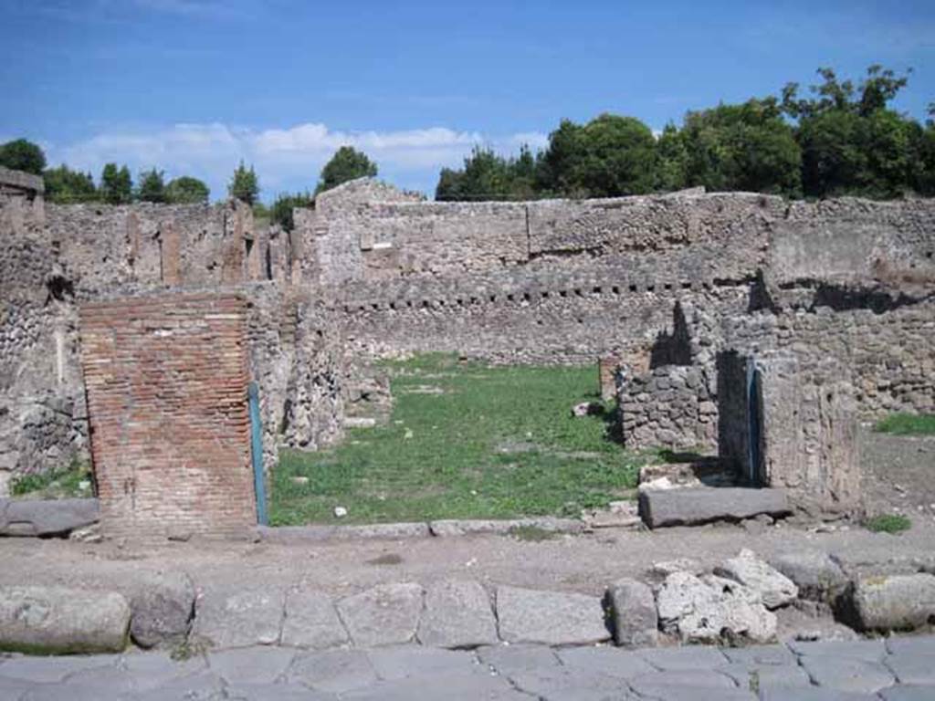 I.1.8 Pompeii. September 2010. Entrance doorway, looking east from Via Stabiana.
The entrance for I.1.7 is on the right side of the entrance). Photo courtesy of Drew Baker.
According to Warscher, quoting Mau in Bull.Inst 1875, p.30, I.1.6-9: “Segue un altro albergo, molto simile a questo descritto. Qui pure è interrotto il marciapiede per lasciar entrare i legni. L’entrata era chiuse mediante una porta a quattro partiti, congiunti a due adue, come si conosce dai quattro buchi per i chiavistelli. Qui pure si entra prima in un compreso che ha le dimensioni d’una bottega grande con una dietrobottega e posteriormente si apre sopra una grande corte, lungo il cui muro di fondo qui pure si stende la stalla, larga 13,30, profonda 2,47 con una finestra sul vico settentrionale e due porte, una all’estremità meridionale, l’altra poco distante da quella settentrionale.
Presso a quest’ultima una parte della corte è selciata. Lungo il muro N vi sono due camere con finestre sul medesimo vico, e prossimo alla stalla il cesso. Si vede anche il cesso del piano superiore e i tubi di mattone d’un terzo, che stava ancora più in alto.
Nell’angolo NO vi sono I primi gradini d’una scala, la cui parte superiore sarà stata di legno, in quello SO l’apertura della cisterna, e accanto nella stessa massa di materiale una vasca lunga stretta e bassa, come quella sudescritta nella casa adiacente. Qui la vediamo frapposto fra la cisterna ed il muro di O, il che esclude categoricamente l’aver essa servito d’abbeveratoio. Dalla parte più bassa di essa, aperta come nella casa sudescritta, l’acqua colava in un’altra vasca larga 1,02 x 1,54, di cui un lato viene formato dalla suddetta massa di fabbrica, uno dal muro occidentale, i due rimanenti da appositi muricciuoli. Essa ha al fondo uno scolo verso N, che dà in un vaso ossia tubo di mattone, incastrato nel suolo. Nella parete vi era la pittura dei Lari, di cui sono rimasti soltanto i serpi. A destra dell’ingresso per i legni sta un locale come una bottega.
L’essere esso congiunto mediante una porta con quel primo compreso, ove entravano i legni, ci lascia supporre, aver esso servito di caupona per i vetturini”.
See Warscher T., 1935. Codex Topographicus Pompeianus: Regio I.1/I.5. Rome: DAIR. (no.14)
(for a translation see, I.1.6).
