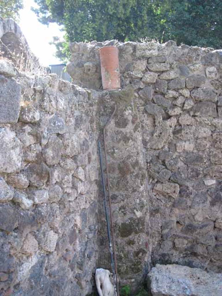 I.1.10 Pompeii. September 2010. Looking west towards south-west corner of room with doorway leading to I.1.1. Detail of feature down-pipe. Photo courtesy of Drew Baker.