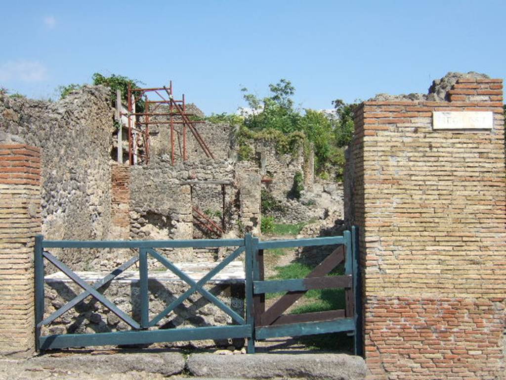 I.2.1 Pompeii. May 2005. Entrance with marble topped counter on north (left) side, on the south side was a hearth. At the rear, the remains of two rooms can be seen, with another rear room east behind the rear room on north side (with scaffolding).