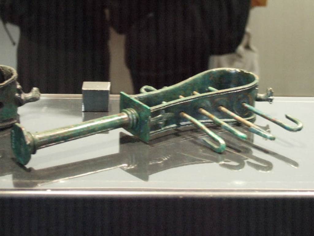 I.2.6 Pompeii. Bronze sistrum found in I.2.6. Now in Naples Archaeological Museum. According to Fiorelli two bronze Sistri were found in the south east corner of the atrium, hanging by iron nails.