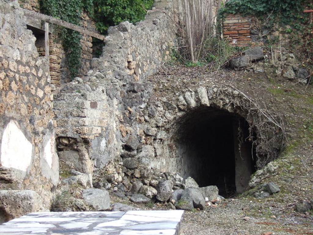 I.2.15 Pompeii. December 2005. Vaulted cistern partly visible from I.2.14. The brick wall at the top of the slope above the cistern marking the end of the corridor from the atrium, together with the remains of the stairs, are the only remains of the area at the west end of the house, that is – steps to upper floor, cupboard, small stable, kitchen and latrine.