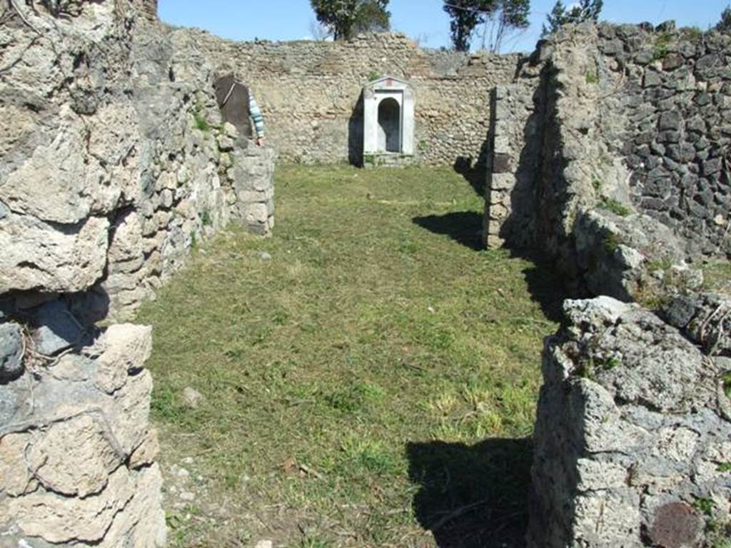 I.2.17 Pompeii. March 2009. Doorway into room 12, oecus, looking east to doorway into room 13, peristyle garden. Warscher writing in her Codex, quoting Mau in Bull. Inst. 1874, p.265, described this as – “Passiamo adesso nel peristilio, accessibile per la seconda camera a sinistra dell’atrio. E desso piuttosto spazioso ed ha portici verso N e O, il cui tetto era sorretto da due pilastri messi insieme, sull’angolo, ed un’altro sul lato di N, ma più verso E, per lasciar libero lo sguardo dal triclinio situato da quella parte. Verso S e E il muro del giardino è diviso in scompartimenti intermediati da altri stretti, in ciascun de’quali è dipinto un candelabro. Invece gli scompartimenti grandi sono riempiti della pittura d’un giardino: un cancello, sormontato in ciascun scompartimento da un’anfora, e dietro di esso un boschetto con uccelli: a destra e a sinistra Ibis e nel mezzo un faggiano.
I portici ed i pilastri hanno una decorazione semplici: senza zoccolo vi sono scompartimenti rossi alternativamente stretti e larghi, alti m. 1,46 divisi da striascie gialle e contornati da linee bianche. Quegli stretti sono abbelliti d’una ghirlanda verticale, mentre fra que’larghi su due troviamo una ghirlanda attaccata colle due estremità, sul resto qualche animale come uccelli ecc”.
See Warscher T., 1935. Codex Topographicus Pompeianus: Regio I.2. (no.31), Rome: DAIR, whose copyright it remains.
(translation: “We go now to the peristyle, accessible by the second room on the left of the atrium. It was rather spacious and had porticoes towards the north and west, whose roof was supported by two pillars linked together on the corner, and another on the north side, but more towards the east, to leave free the view from the triclinium situated at that part. Towards the south and east, the wall of the garden was divided into compartments, between which were narrow ones, in each of which a candelabra was painted. The large compartments instead were filled with a painting of a garden: a gate, surmounted in each compartment by an amphora, and behind it a wood with birds: Ibis were to the right and to the left, and in the middle a pheasant. The porticoes and pilasters had a simple decoration: without a zoccolo, there were red alternately narrow and wide compartments, 1,46m high, divided by yellow stripes and surrounded by white lines. The narrow ones were embellished with a vertical garland, while between those wide on two were found a garland attached with the two ends, on the rest some animals, like birds, etc.”)