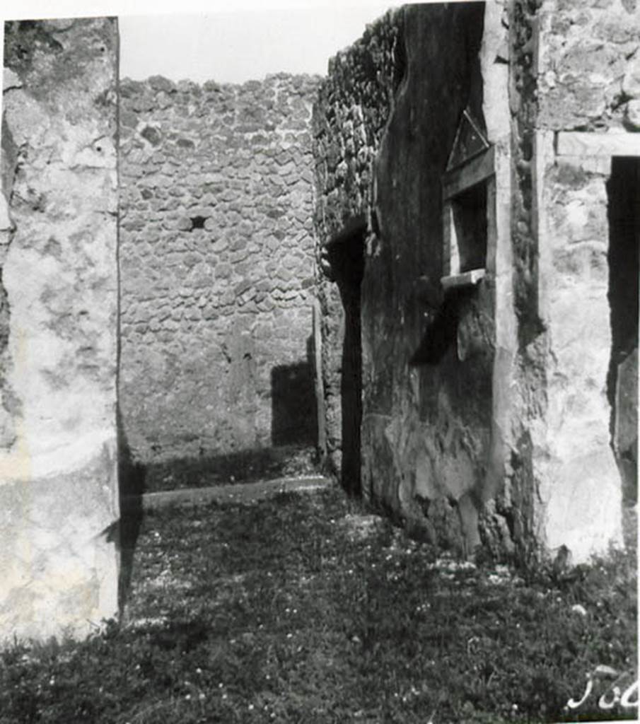 1.2.17 Pompeii. 1935 photo taken by Tatiana Warscher. Looking north along entrance corridor towards doorway.
See Warscher T., 1935. Codex Topographicus Pompeianus: Regio I.2. (no.28), Rome: DAIR, whose copyright it remains.
According to Warscher, quoting Bull. Inst, 1874, p.264 – I.2.17 “La fauces che hanno la soglia di lava, s’abbassano un poco verso l’interno. Nel muro sinistra vi è una piccola nicchia con suole e cornice di marmo a guisa d’un tempietto. Nel suole di essa sono tre buchi, uno più profondo degli altri destinati probabilmente per mettervi piccoli idoli, come la lastra sporgente del suolo serviva per oblazioni. Presso gli angoli che formano le fauces coll’atrio manca lo stucco del muro, e nel suolo su ciascun lato si vede una pietra di lava: evidentemente vi stavano li postes di legno”.
(translation: I.2.17 “The fauces that had a threshold of lava, led slightly downwards towards the atrium. In the left wall there was a small niche with floor and cornice of marble, in the guise of a shrine. In the floor were three holes, one deeper than the others, which was used probably for a small idol, and the protruding slab of the floor was used for donations. Near the corner that joined the fauces with the atrium, the wall stucco was missing and in the floor on that side one could see a slab of lava: evidently there were wooden posts”.)