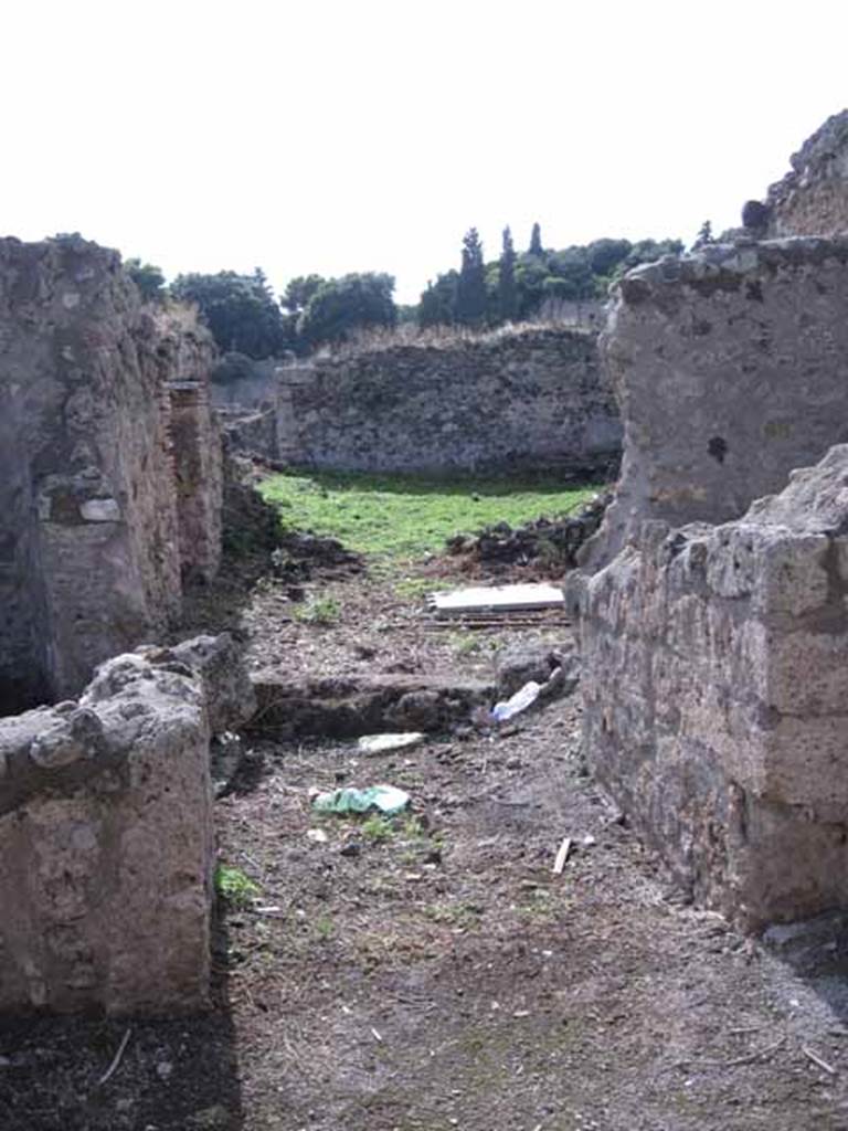 I.2.20 Pompeii. September 2010. Looking west towards entrance doorway. Photo courtesy of Drew Baker. According to Warscher, quoting Fiorelli, she described –
“Entrambi I due aditi appartenevano ad una caupona, cui era congiunto un thermopolium. La caupona no.20 teneva a destra dell’androne una cella, e poi un cortile con banco di fabbrica per sedere: a sinistra la cucina, la latrina, il pozzo, ed un piccola apotheca, dove rimangono ancora sulle pareti i chiodi di sostegno alle scansie. Il cortile, o atrio che voglia dirsi, veniva illuminato da un finestra sporgente in un attiguo viridario, il cui ambulacro sottoposto ad un tettoia, conduceva al triclinio, ad un scaletta montante ai cenacoli, e ad altre due celle destinate forse agli avventori. Addossati ad un angolo del viridario stanno due letti triclinarii di fabbrica, con la loro mensa, e sulla parete accosto è tracciata col carbone, di mezzo a varie epigrafi, una testa muliebre di grandezza maggiore del vero, forse di quella stessa Serena, che forni argomento a varie di queste scritture. Sulla parete a destra vedesi il sacrario dei Penati, consistente di una nicchia, presso cui è l’immagine di un grosso serpente cristato, che passa fra varie piante e si avvicina ad una mensa, sulla quale stanno imbandite varie frutta ed una pigna: superiormente sono effigiati Bacco e la Fortuna, ai lati dei globo terrestro, cui è adossata la luna crescente sormontata dall’astro, e tutto sotto due festoni di foglia”.
See Fiorelli, Descrizione, p.45/46.
See Pappalardo, U., 2001. La Descrizione di Pompei per Giuseppe Fiorelli (1875). Napoli: Massa Editore. (p.36)
See Warscher T., 1935. Codex Topographicus Pompeianus: Regio I.2. Rome: DAIR, whose copyright it remains
(translation: “Both the two accesses belonged to one caupona, which was joined to the thermopolium. On the right of the entrance doorway to the caupona at no.20 was a room, and then a courtyard with a masonry bench for sitting: on the left, the kitchen, latrine, the well, and a small storeroom, where the nails to support shelving on the walls still remained. The courtyard, or atrium, was illuminated by a projecting window in an adjoining garden, whose walkway under a roof, led to the triclinium, to a stairway going up to the upper dining rooms, and to another two rooms destined perhaps for the patrons. Close to a corner of the garden were two masonry triclinium couches, with their table, and on the wall nearby was drawn with charcoal, among various other epigraphs, a head of a woman, larger than life, maybe that of the same Serena that was mentioned in several of these writings. On the wall to the right, we see the shrine of the Penates, consisting of a niche, near to which was the image of a crested serpent, that passed between various plants while approaching a table, on which were laid out various fruits and a pine-cone: above were the effigies of Bacchus and Fortuna, to the side of the terrestrial globe which was attached to the crescent moon with a star above it, above all were two garlands of foliage”.)